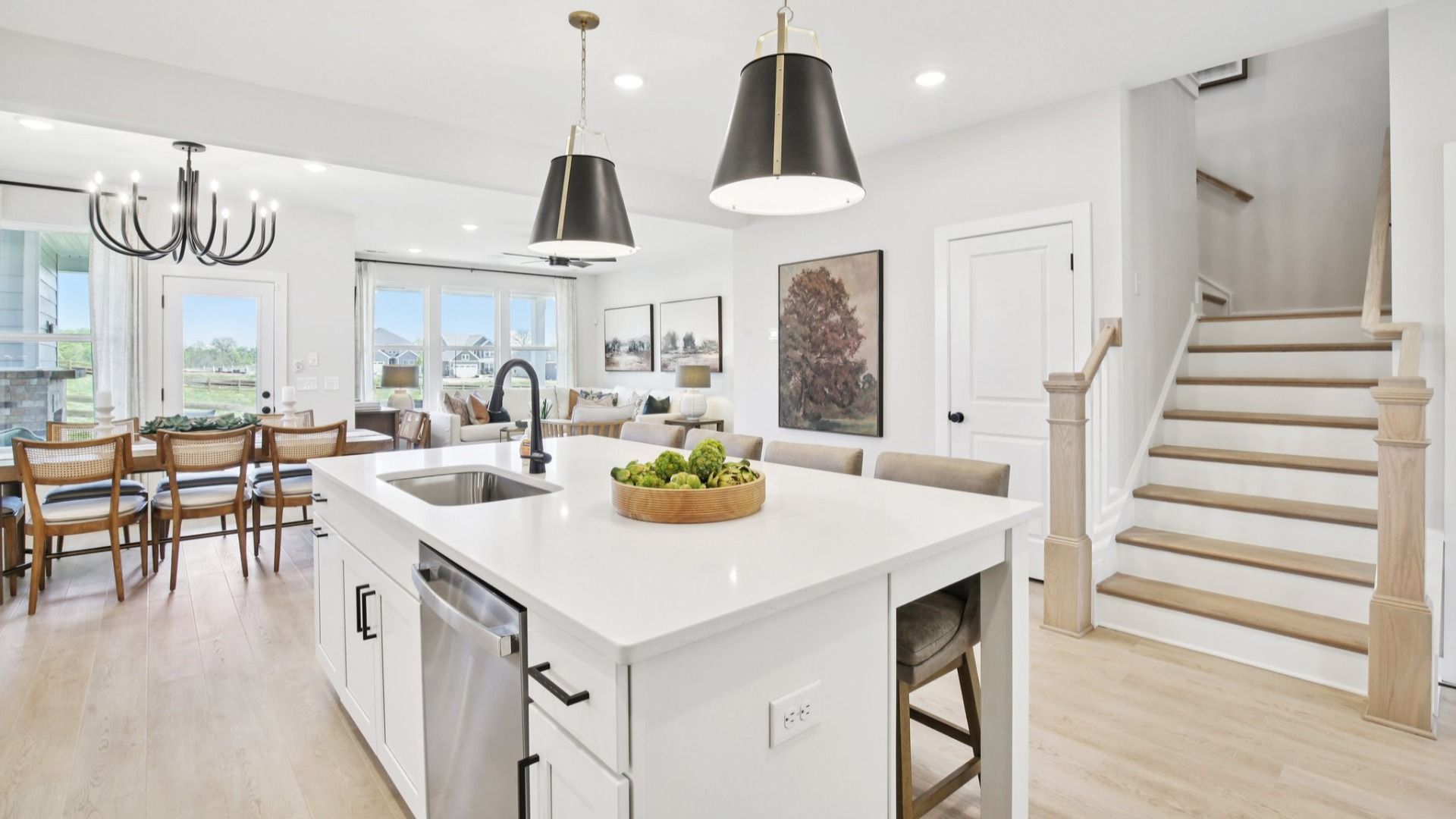 View from kitchen of dining area, gathering room, and staircase to second floor