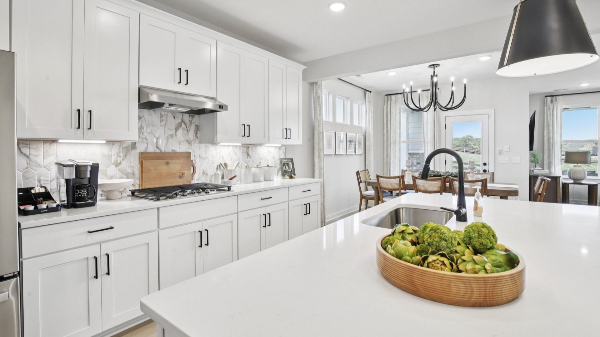 Bright white kitchen cabinets with quartz countertops and ceramic tile backsplash