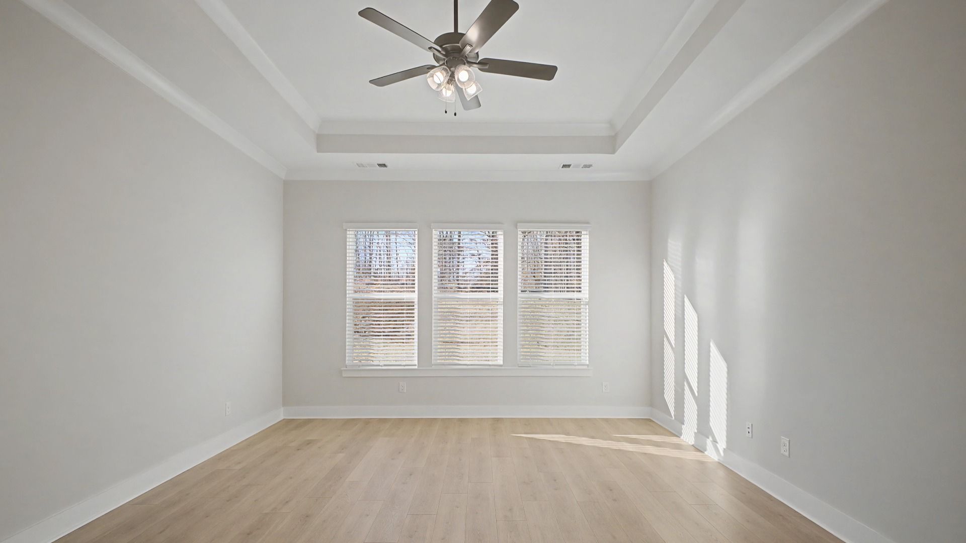 Primary Bedroom with tray ceiling, windows, and ceiling fan