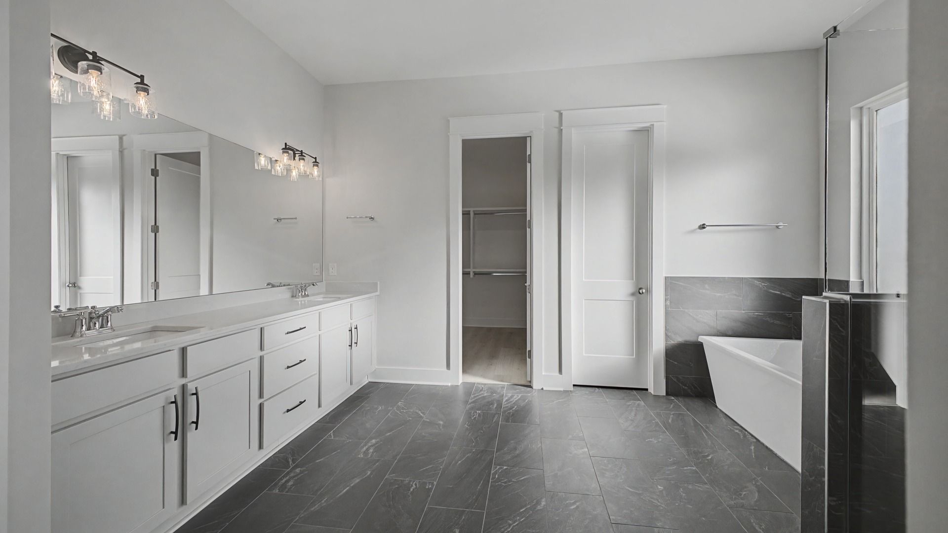 Large en-suite primary bath with tiled floor, double vanity, glass shower, and freestanding tub