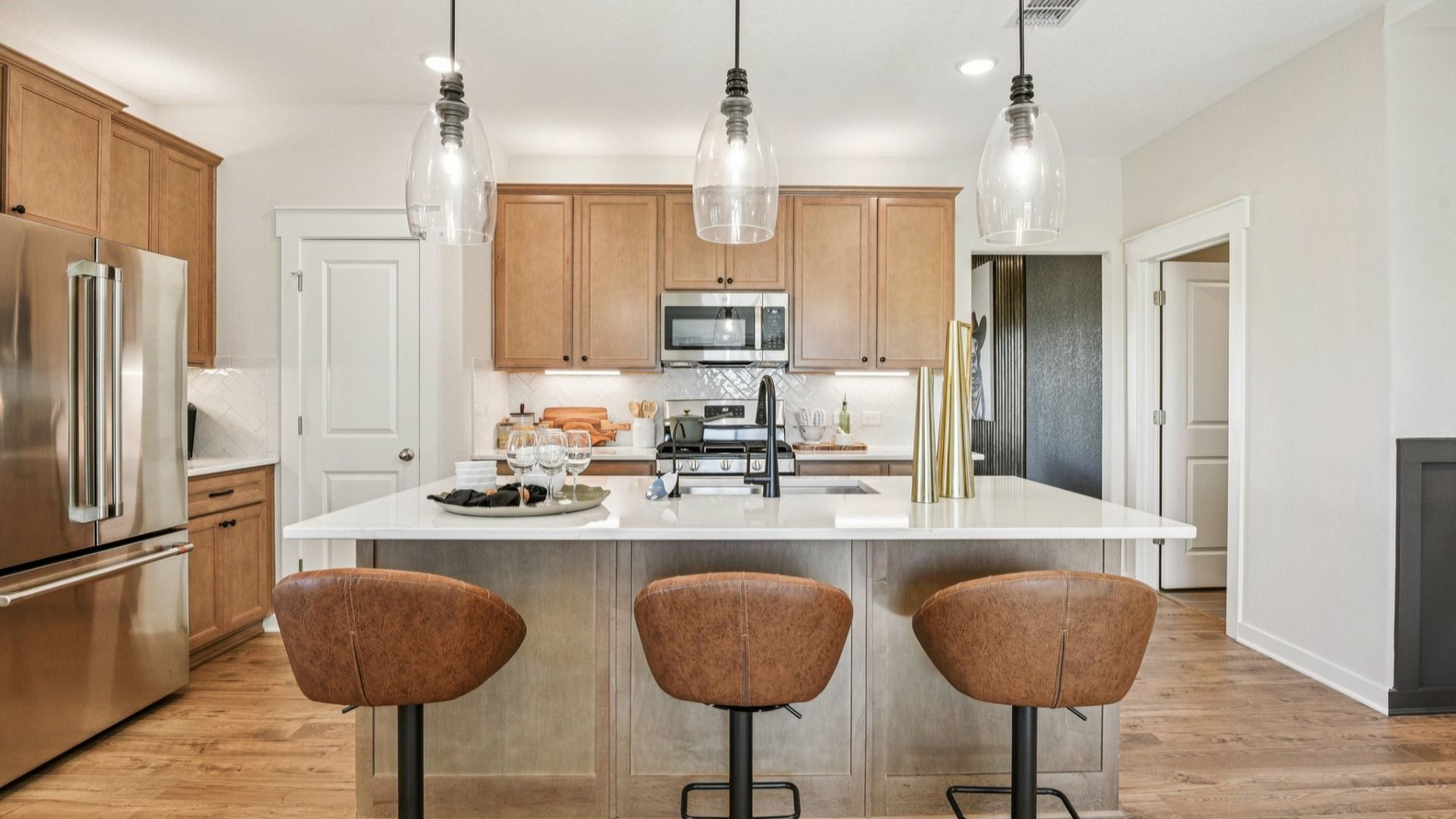 The kitchen features 42 inch wood cabinetry with industrial style pendant lighting above the center island