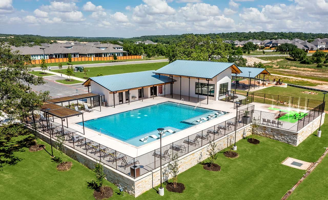 Experience luxury at Meyer Ranch's pool, featuring sleek stonework, blue roofing, and modern amenities amidst lush greenery.
