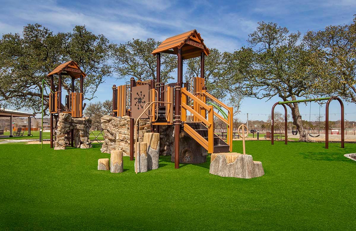 This distinctive playground features premium wooden structures set against vibrant greenery at Meyer Ranch.