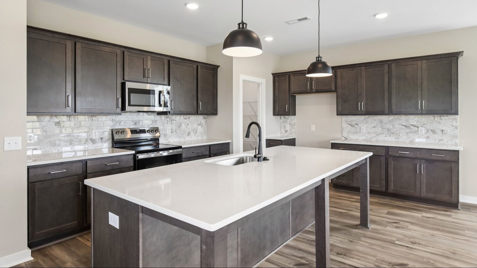 Kitchen with dark cabinetry, quartz countertops, and tile backsplash