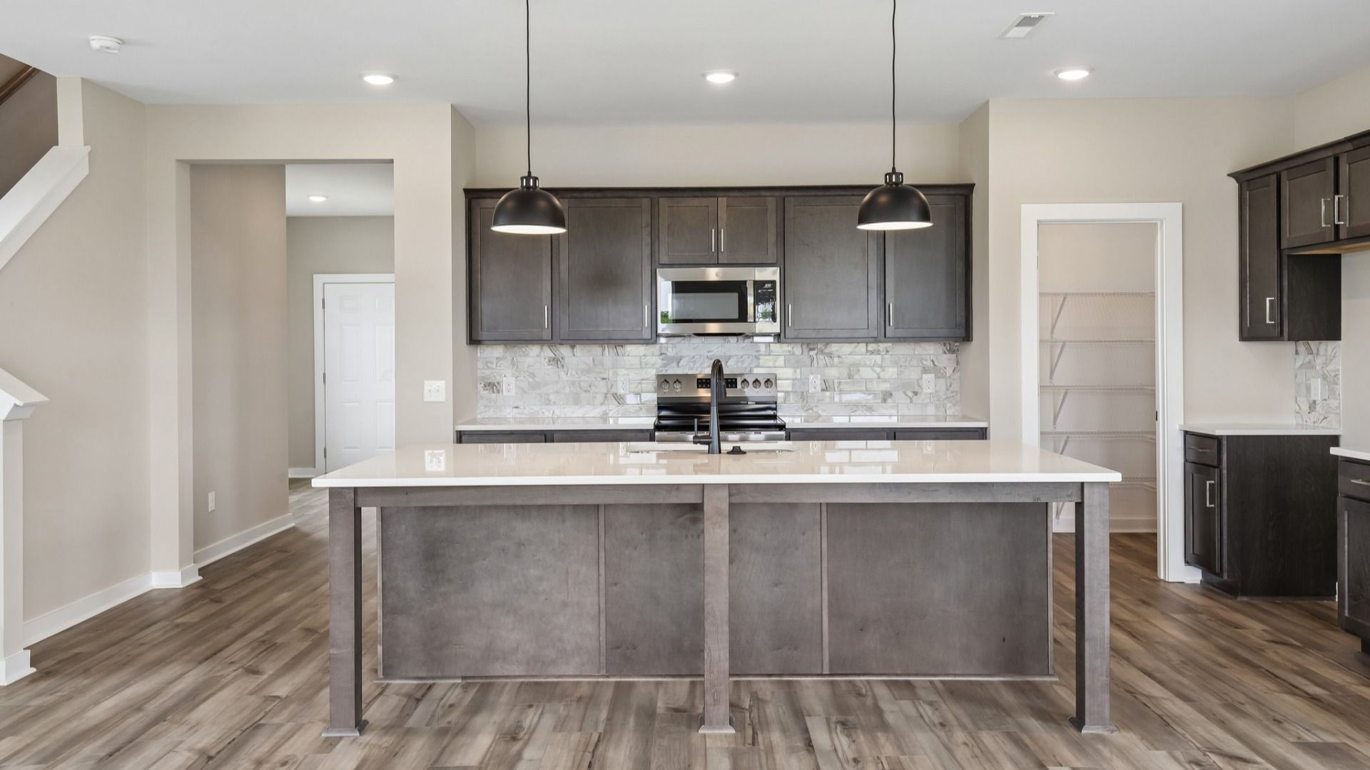 Kitchen with dark cabinetry, quartz countertops, and tile backsplash