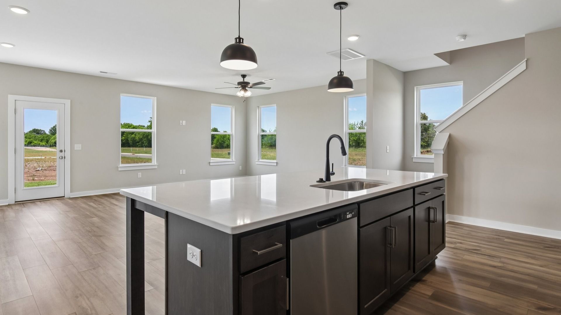 Kitchen with dark cabinetry, quartz countertops, and view of gathering room