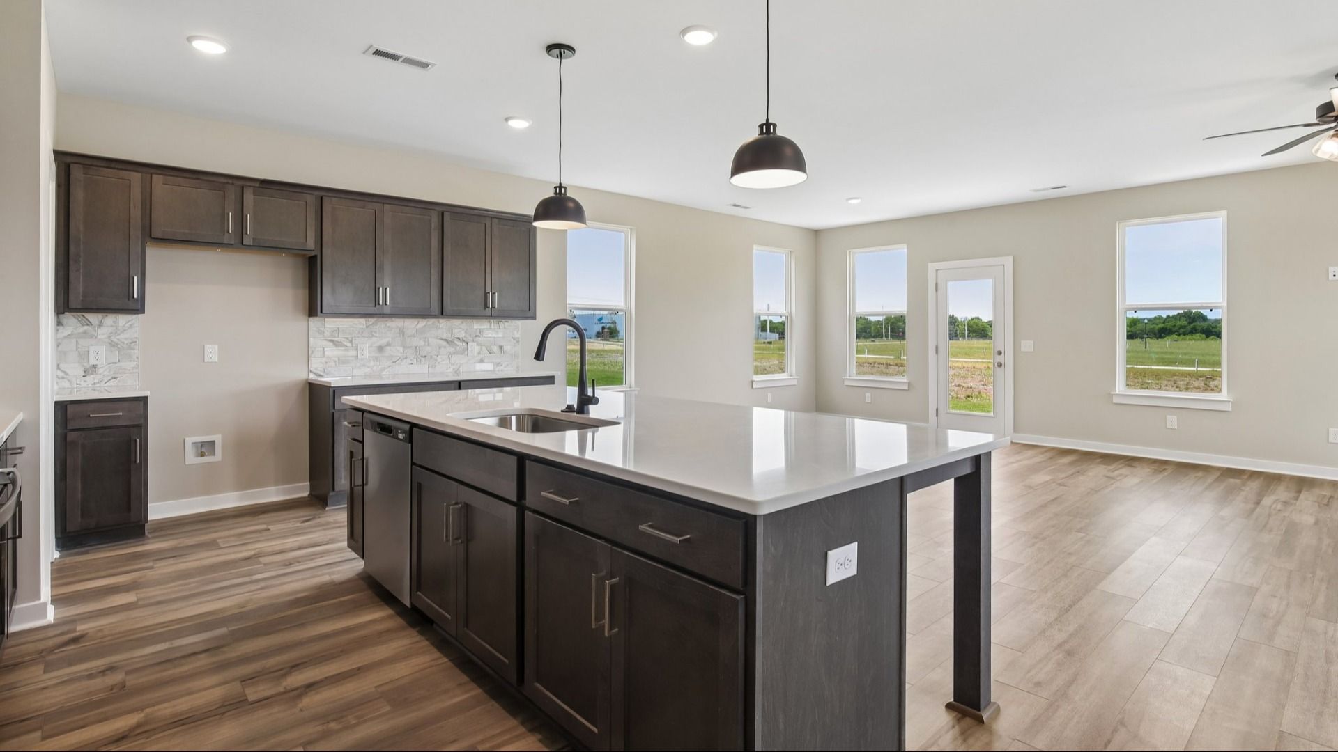 Kitchen with dark cabinetry, quartz countertops, and view of gathering room