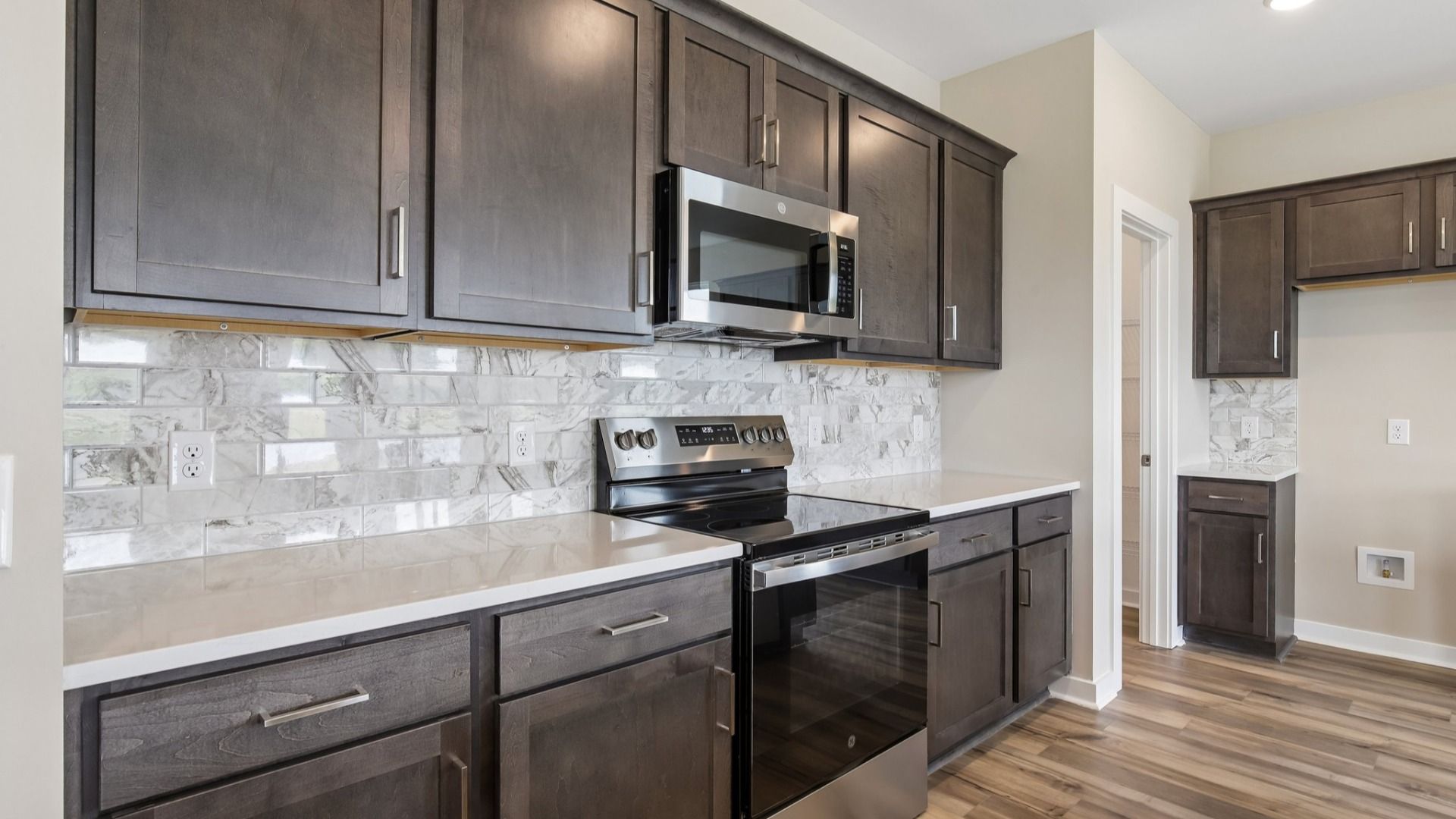 Kitchen with dark cabinetry, quartz countertops, and tile backsplash