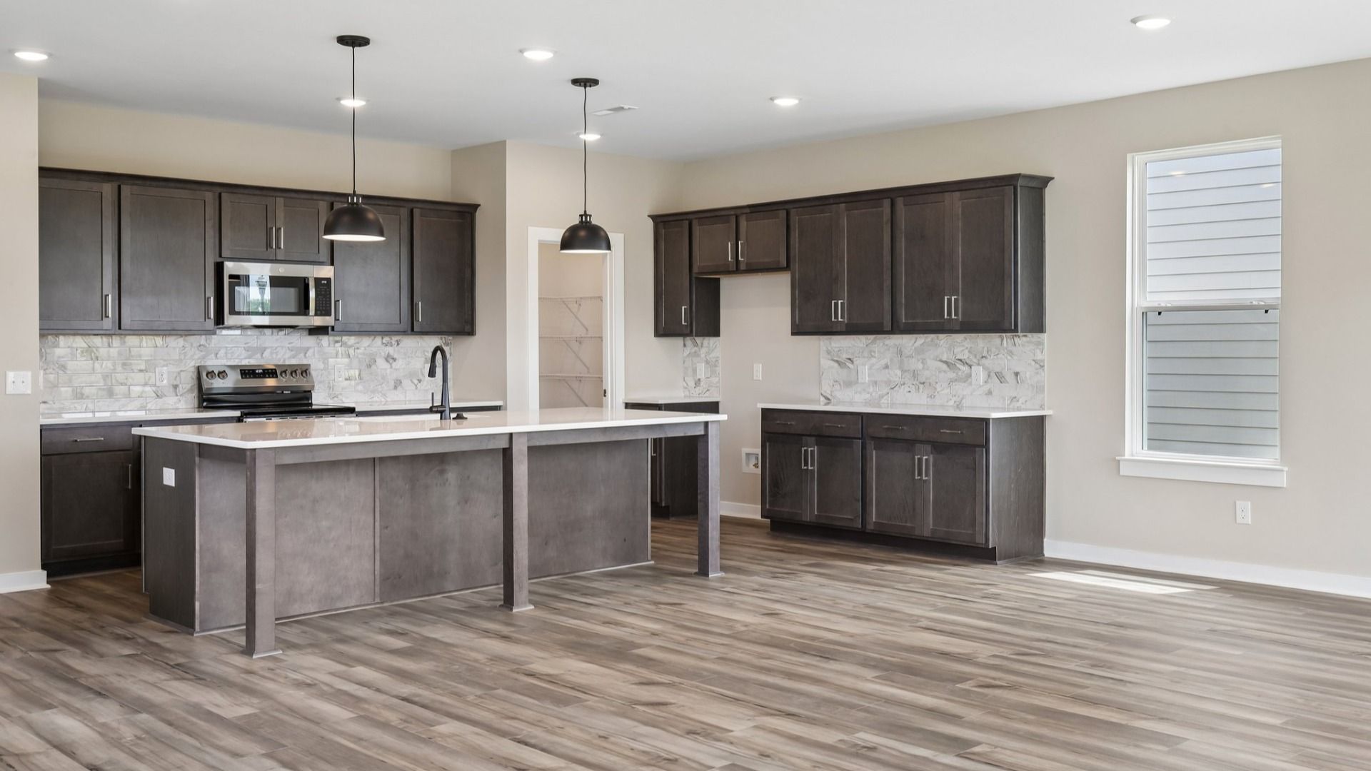 Kitchen with dark cabinetry, quartz countertops, and tile backsplash