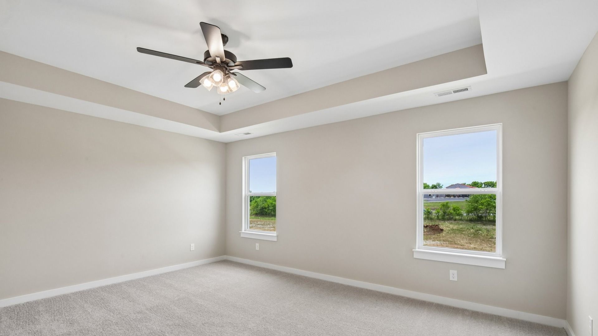Bedroom with tray ceiling, windows, and ceiling fan