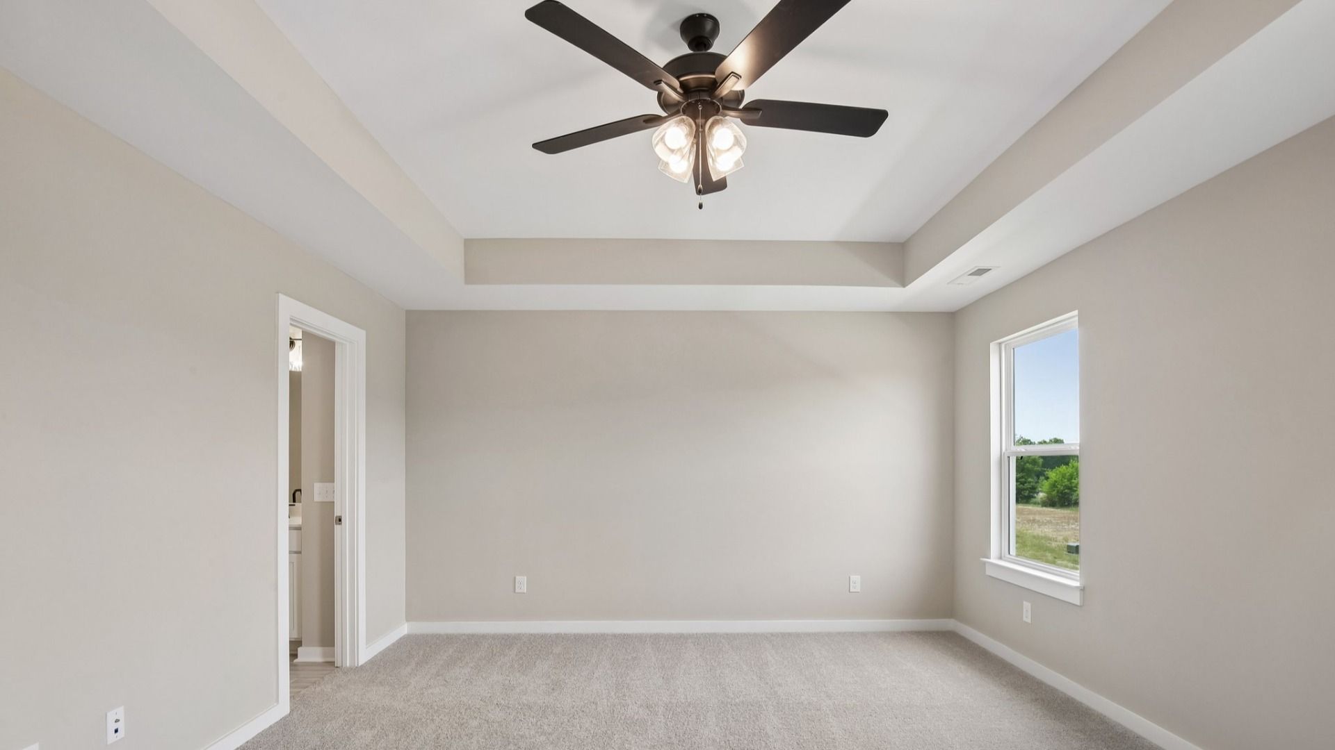 Bedroom with tray ceiling, windows, and ceiling fan
