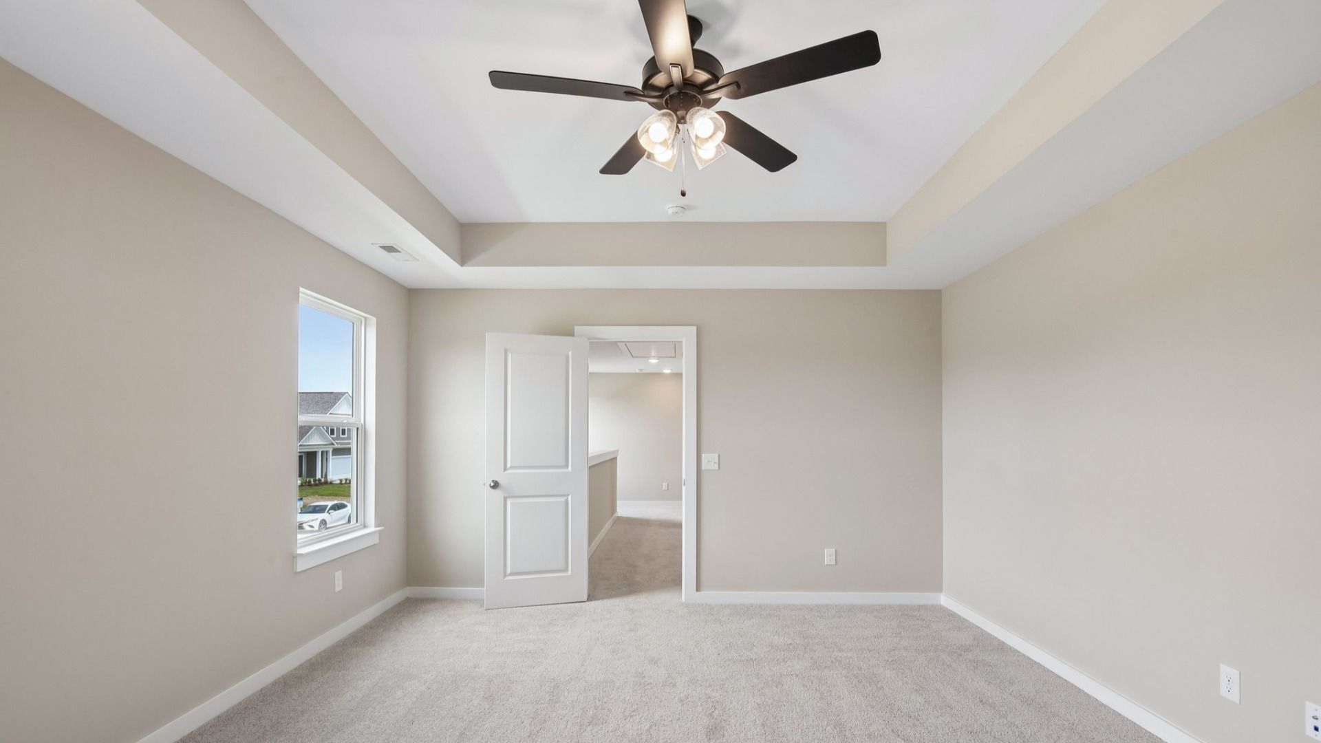 Bedroom with tray ceiling, windows, and entrance to primary bedroom