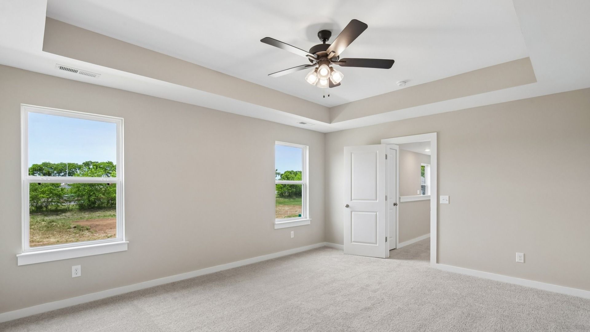Bedroom with tray ceiling, windows, and entrance to primary bedroom