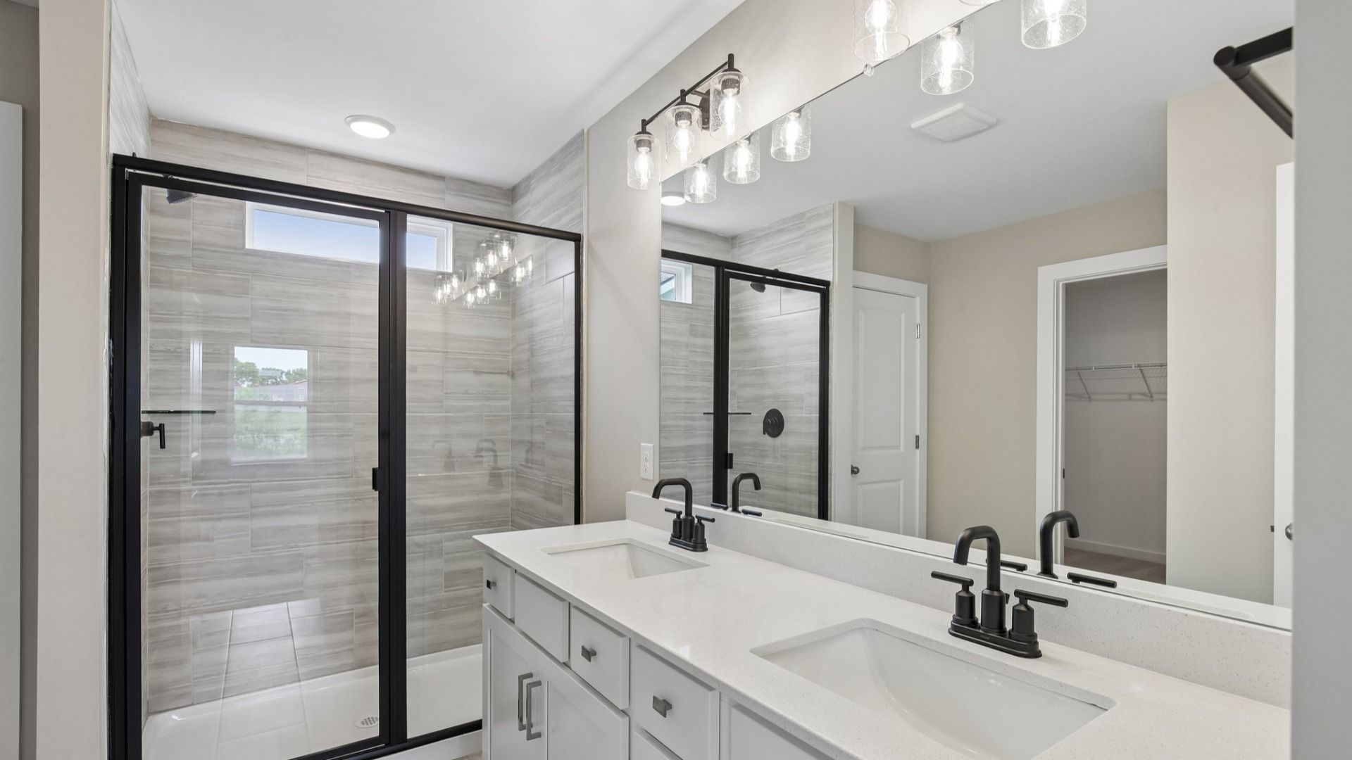 Bathroom with tile shower and glass enclosure, along with dual vanity