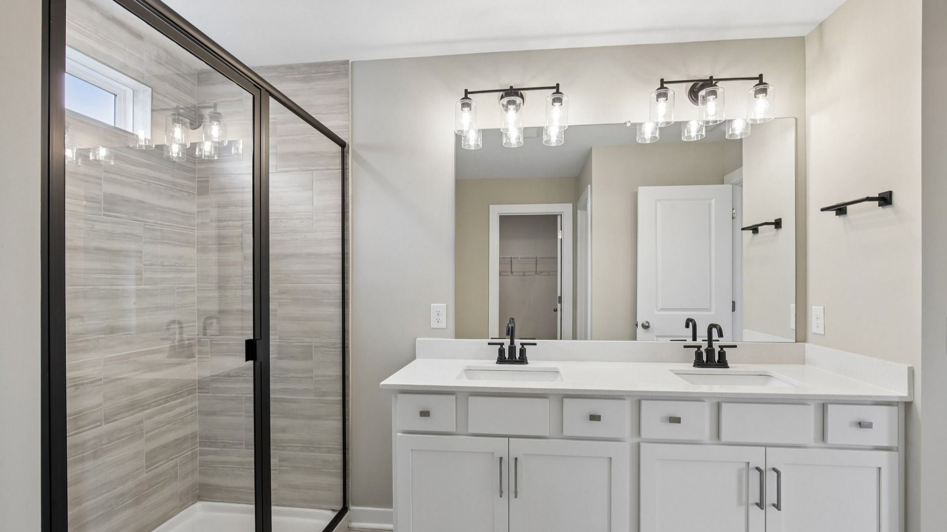 Bathroom with tile shower and glass enclosure, along with dual vanity