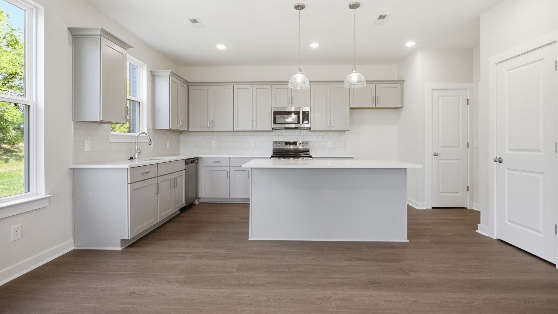 Kitchen with light cabinetry, quartz countertops, tile backsplash, and pantry