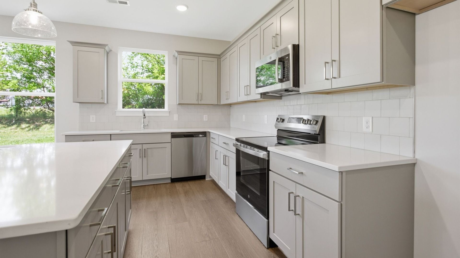 Kitchen with light cabinetry, quartz countertops, tile backsplash, and pendant lighting