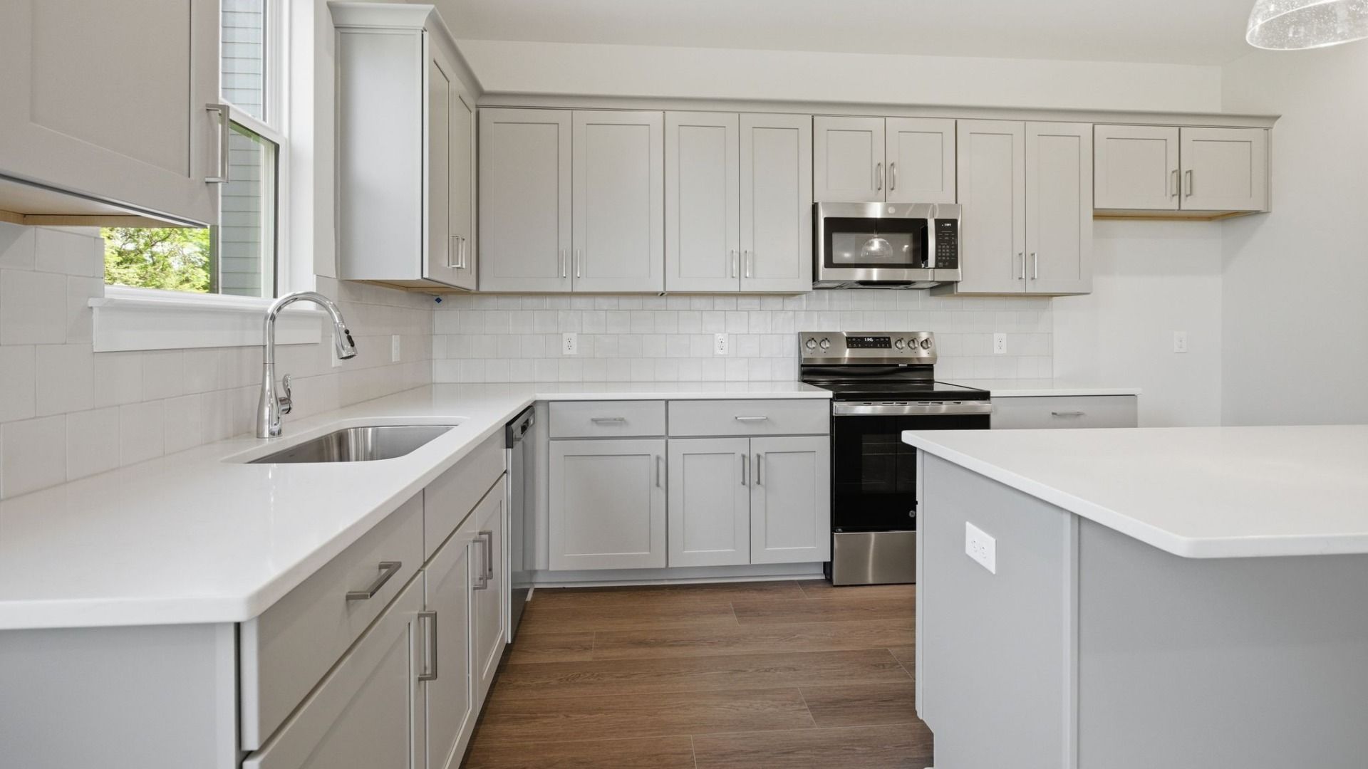 Kitchen with light cabinetry, quartz countertops, and tile backsplash