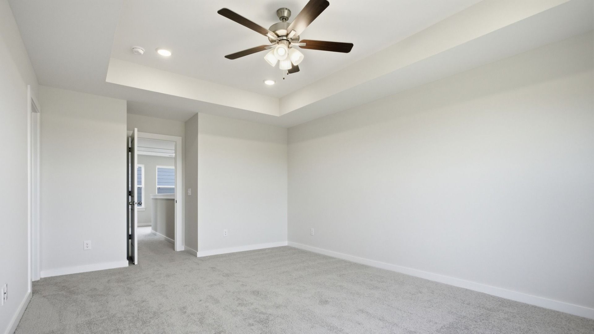 Bedroom with tray ceiling, ceiling fan, and entry to second floor