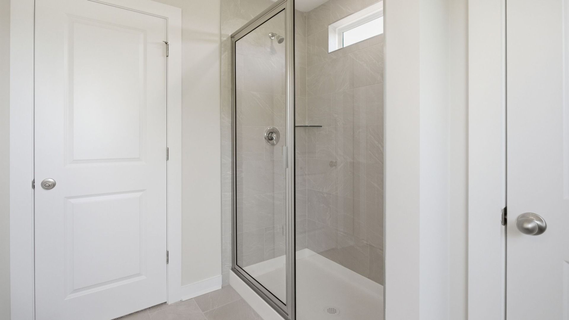 Bathroom with glass enclosed shower with bright natural light from window