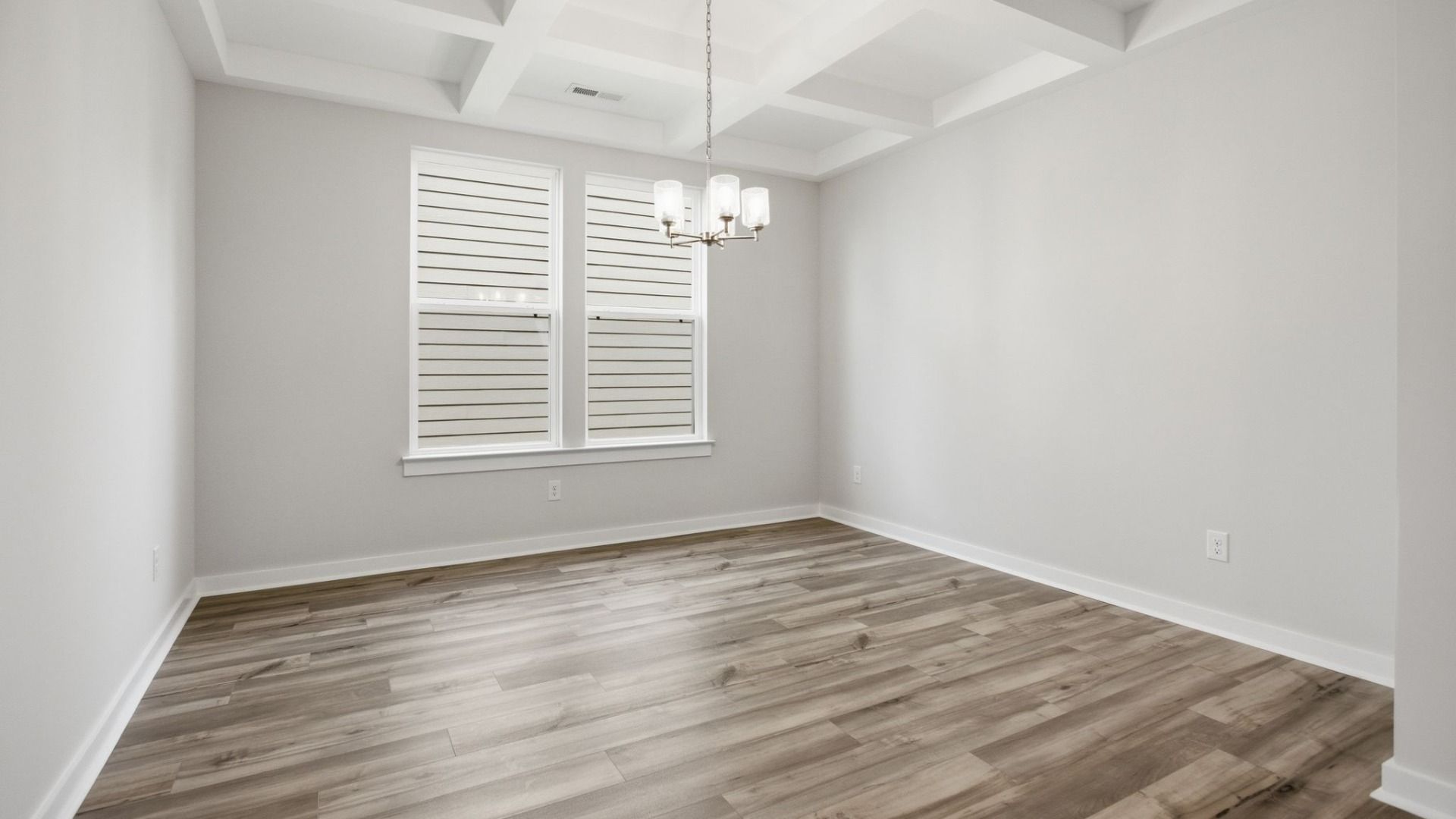 Dining Room with two windows, chandelier, coffered ceiling trim, and hard surface flooring