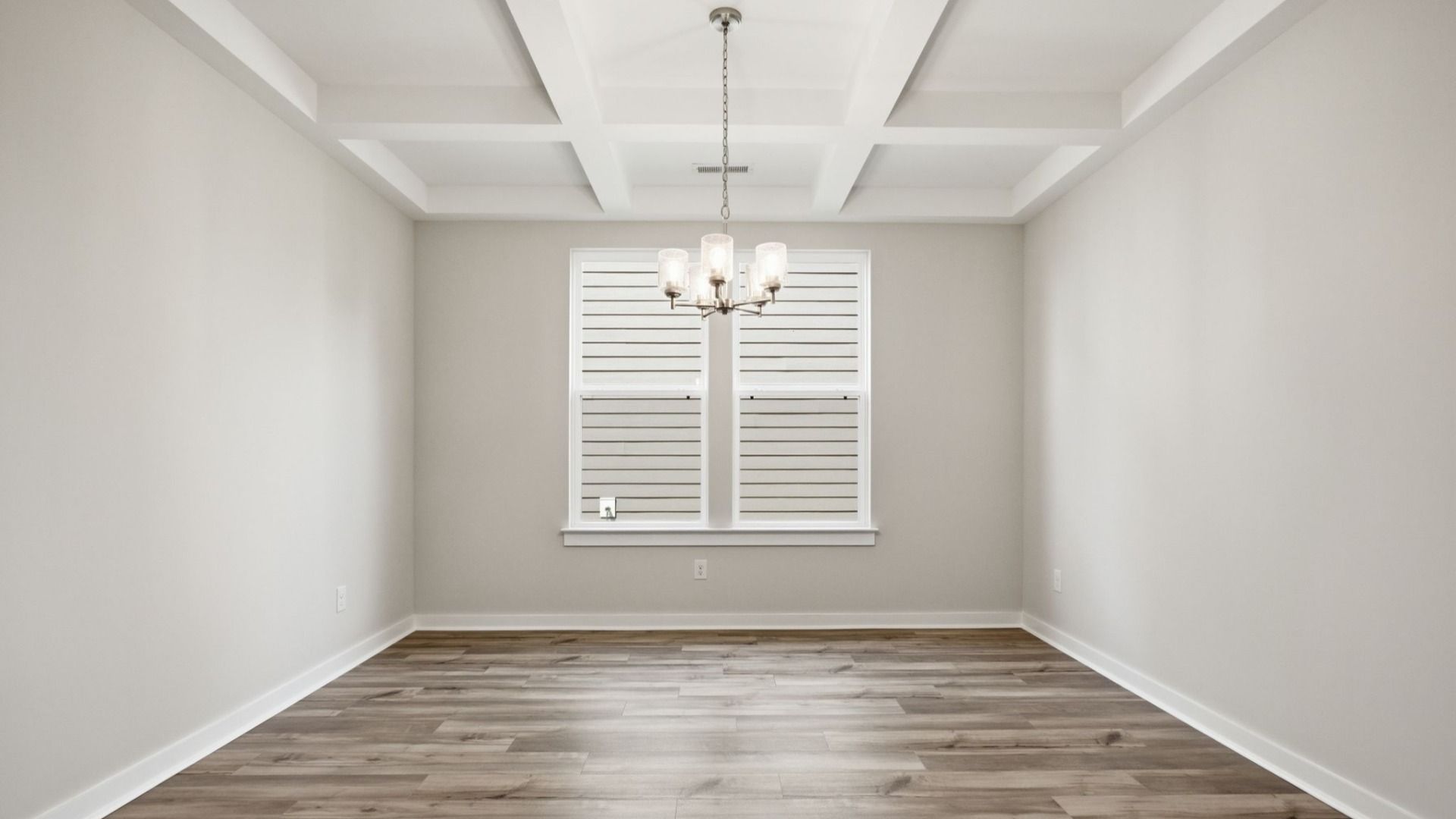 Dining Room with two windows, chandelier, coffered ceiling trim, and hard surface flooring