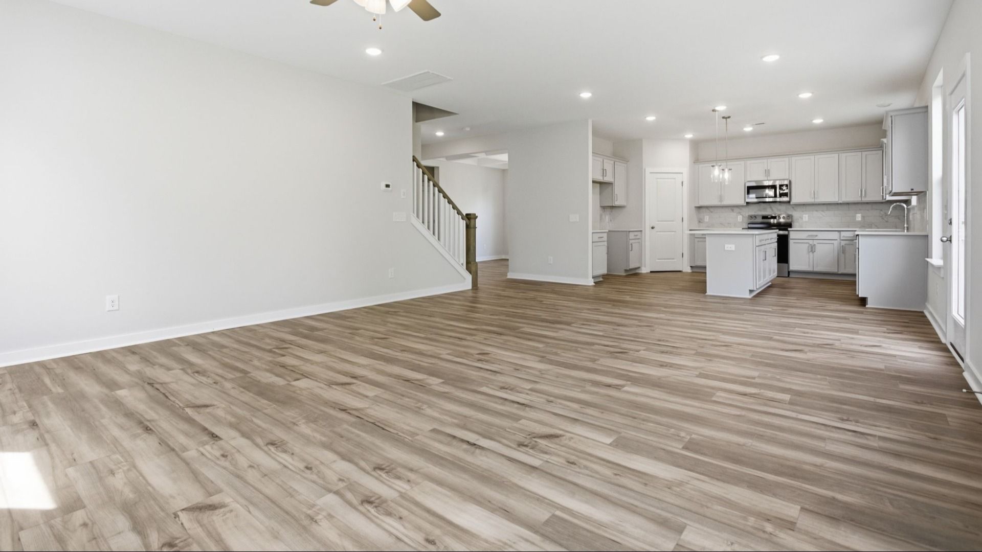 First floor with hard surface flooring, windows, nearby staircase, and view into the kitchen