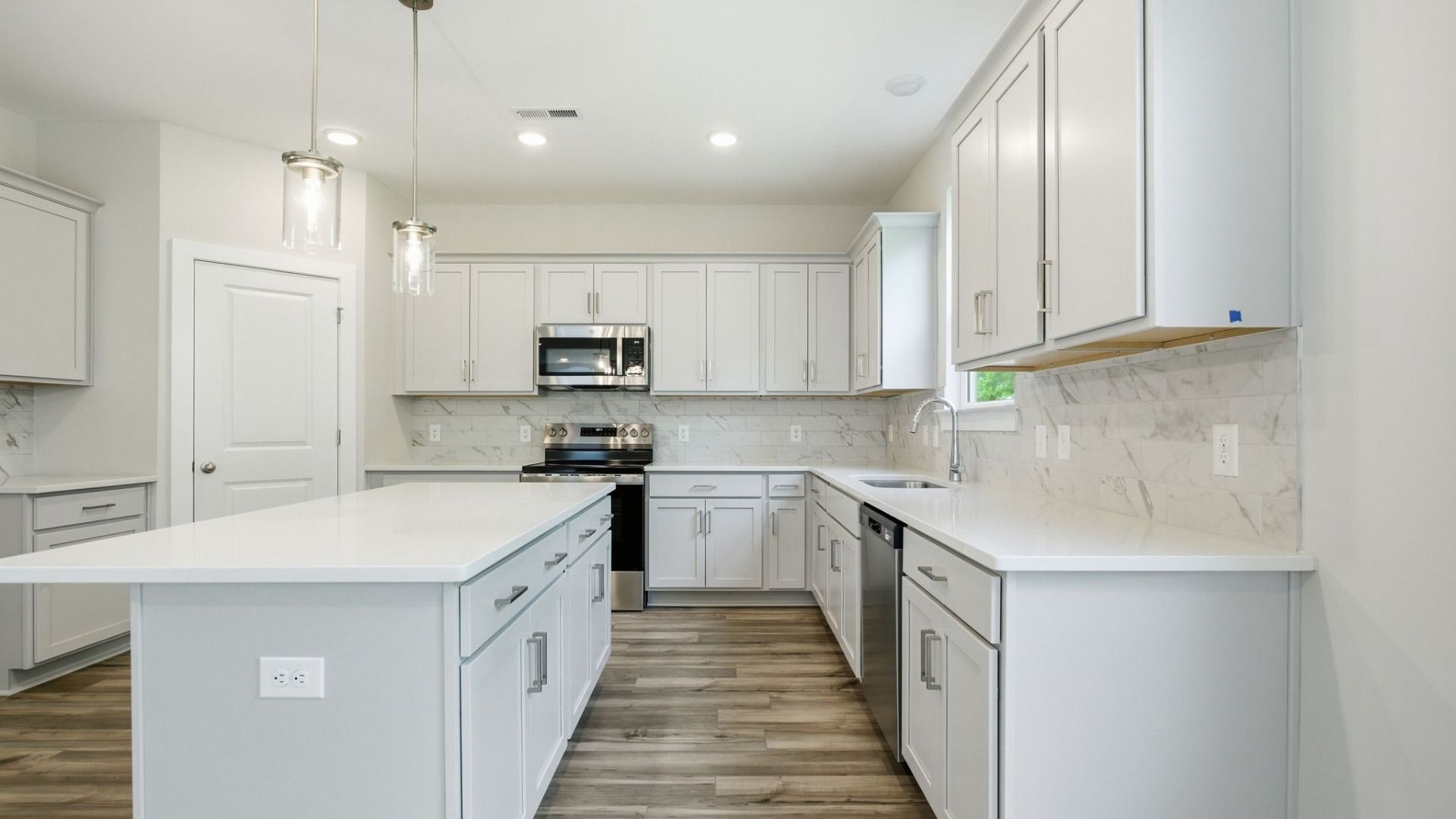 Kitchen with light cabinetry, quartz countertops, tile backsplash, and pantry