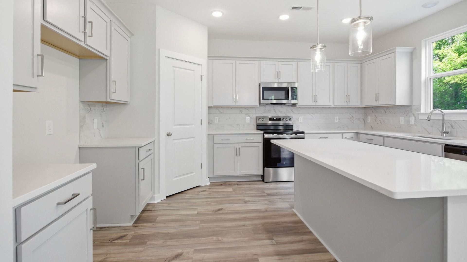 Kitchen with light cabinetry, quartz countertops, tile backsplash, pantry, and window