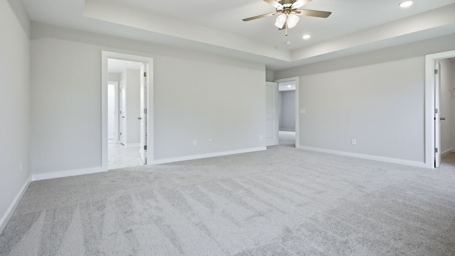 Bedroom with tray ceiling, ceiling fan, and access to primary bathroom, closet, and loft area