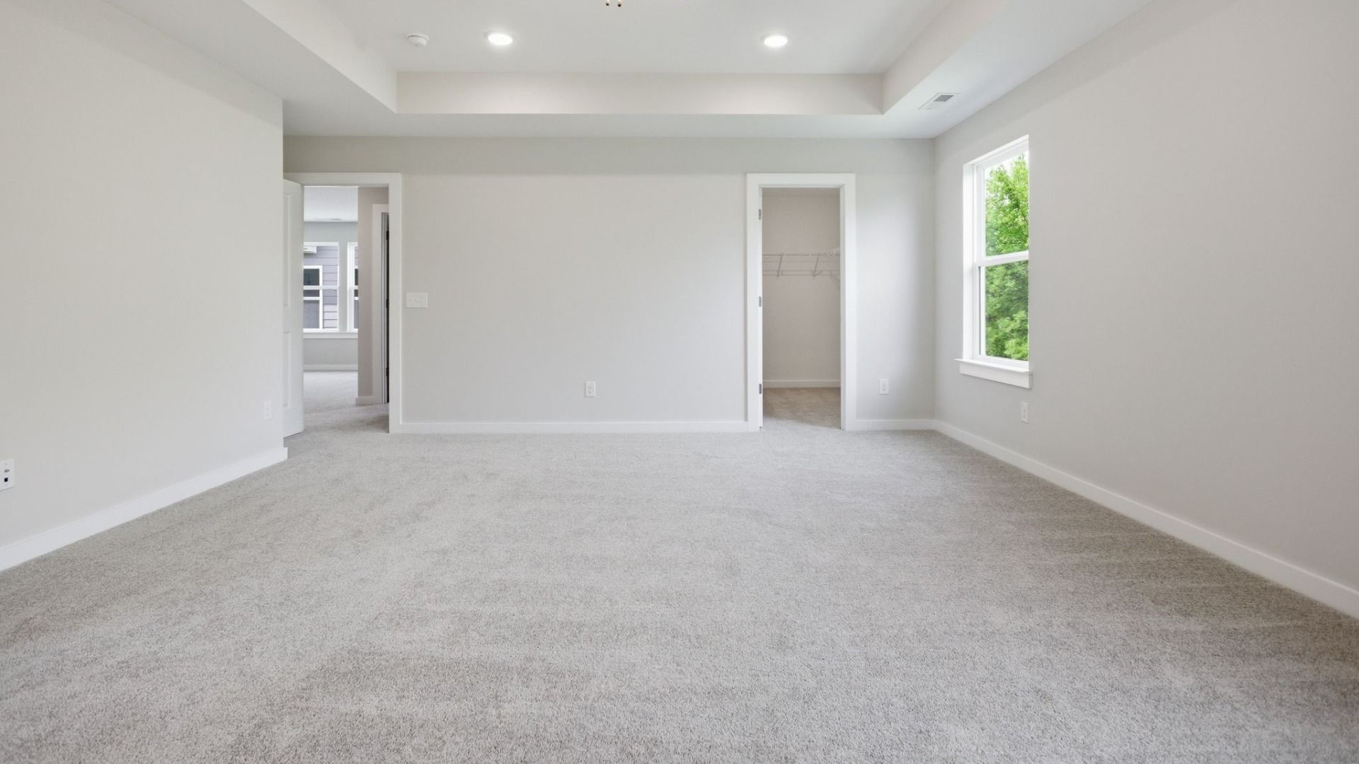 Bedroom with tray ceiling, window, and access to closet and loft area