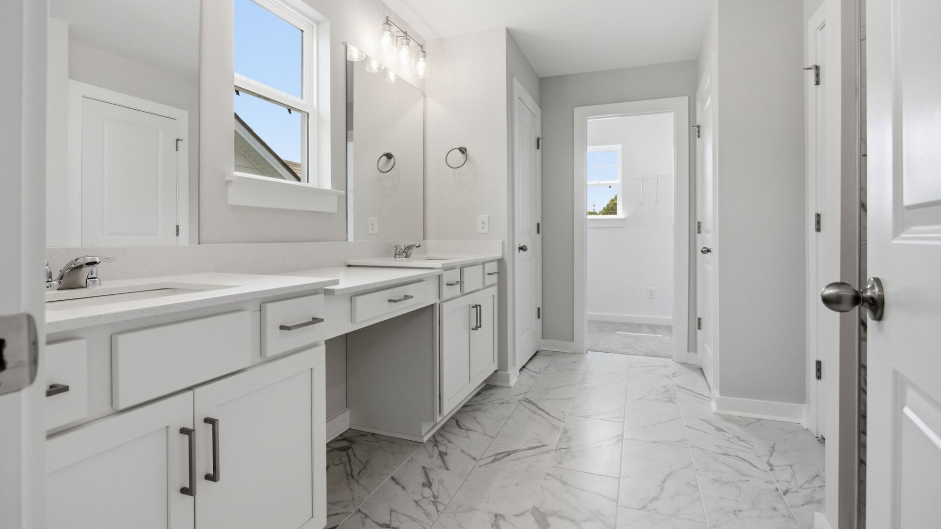Bathroom with access to closet, dual vanity, and window