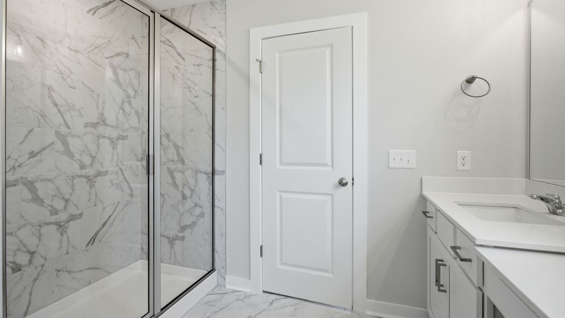 Bathroom with glass enclosed tile shower leading to primary suite