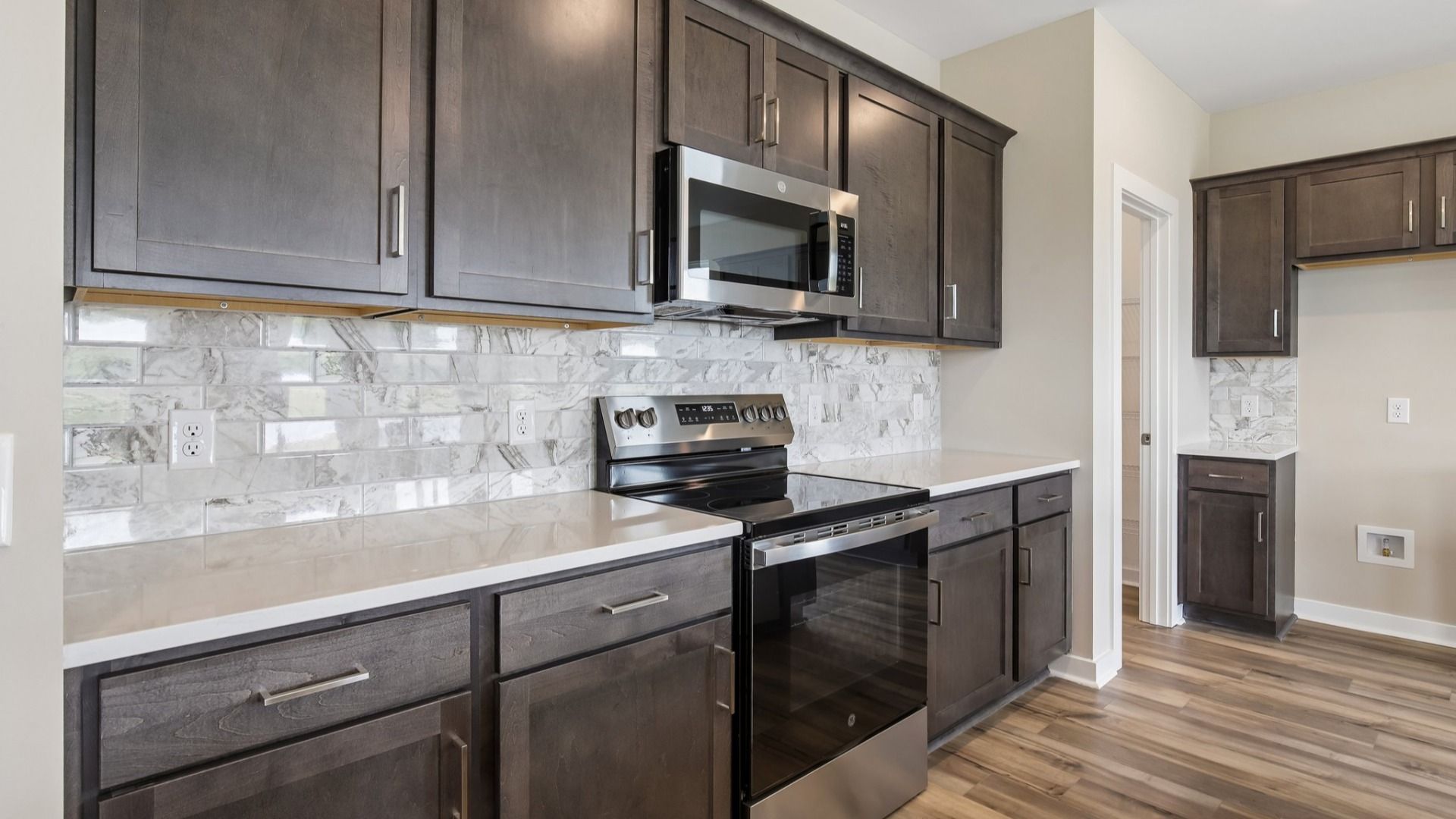 Kitchen with dark cabinetry, quartz countertops, and tile backsplash