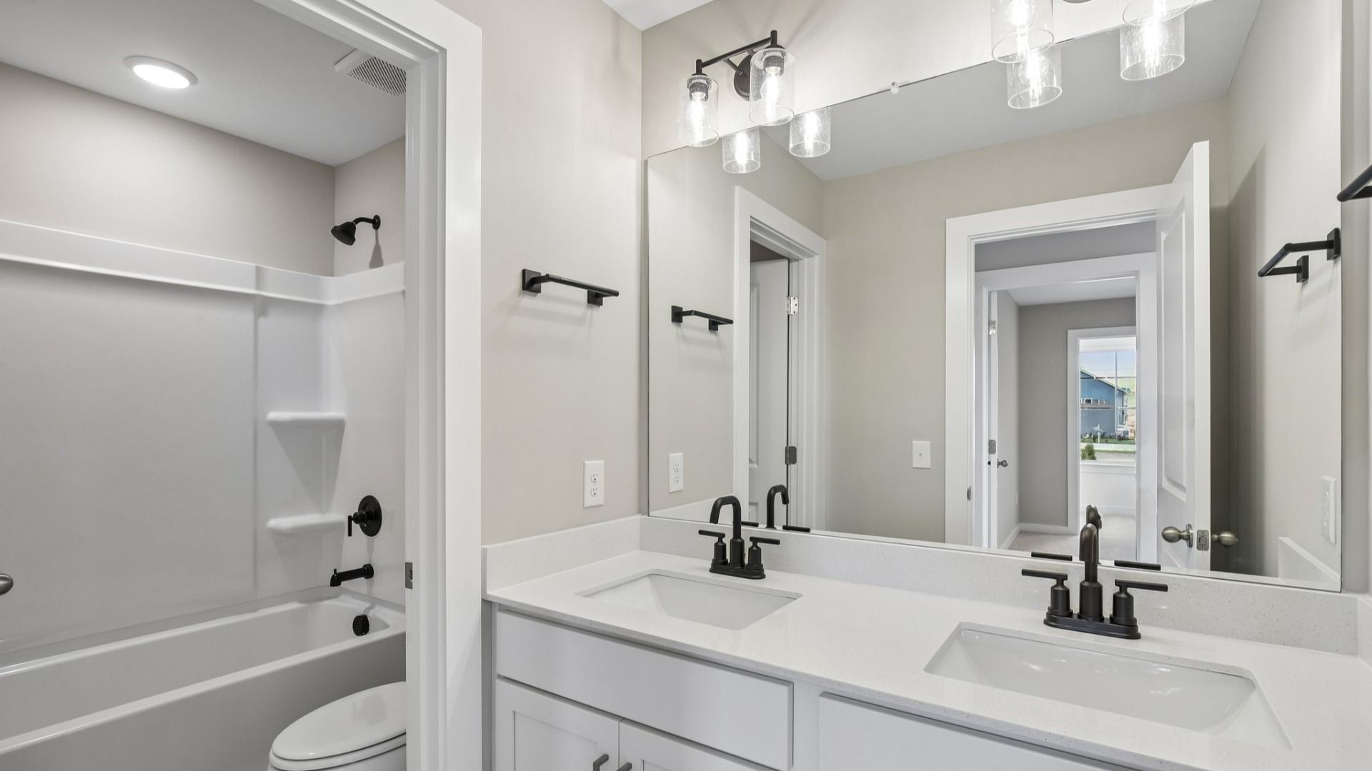 Secondary Bathroom with dual vanity and door to shower and toilet