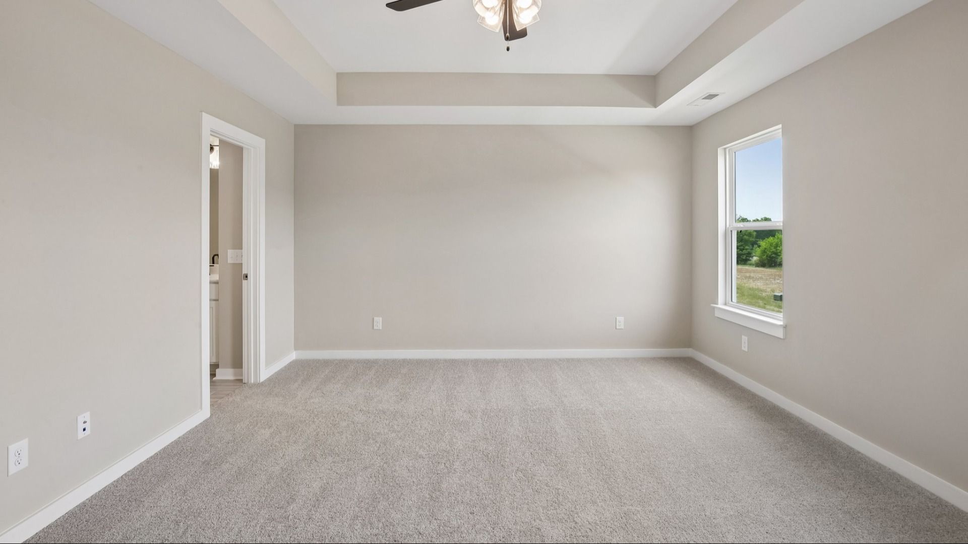 Bedroom with tray ceiling, windows, and ceiling fan