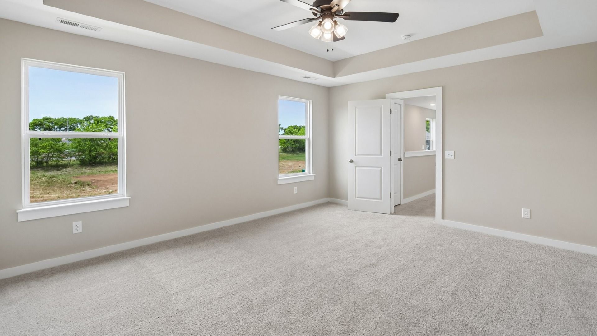 Bedroom with tray ceiling, windows, and entrance to primary bedroom