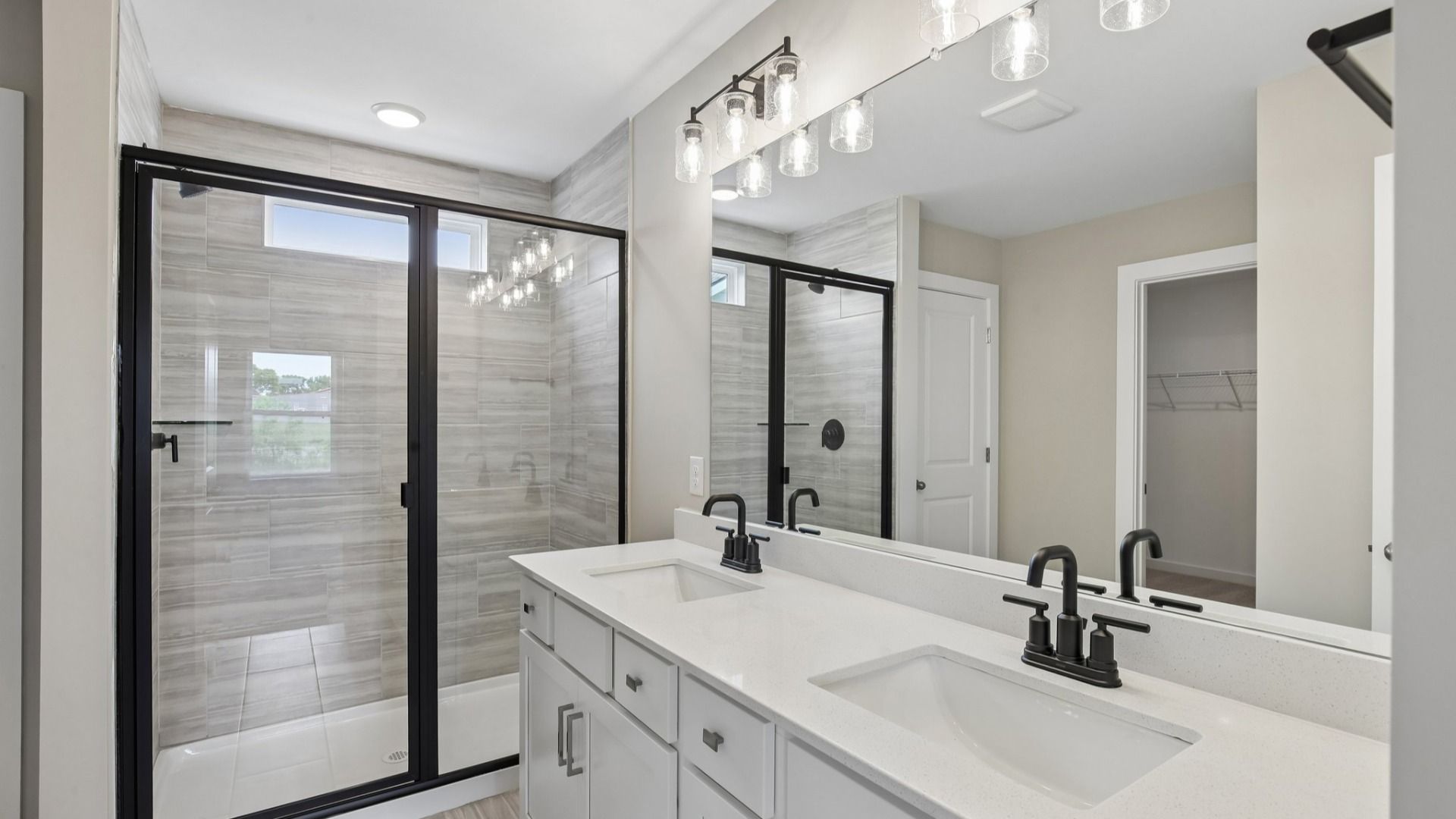 Bathroom with tile shower and glass enclosure, along with dual vanity