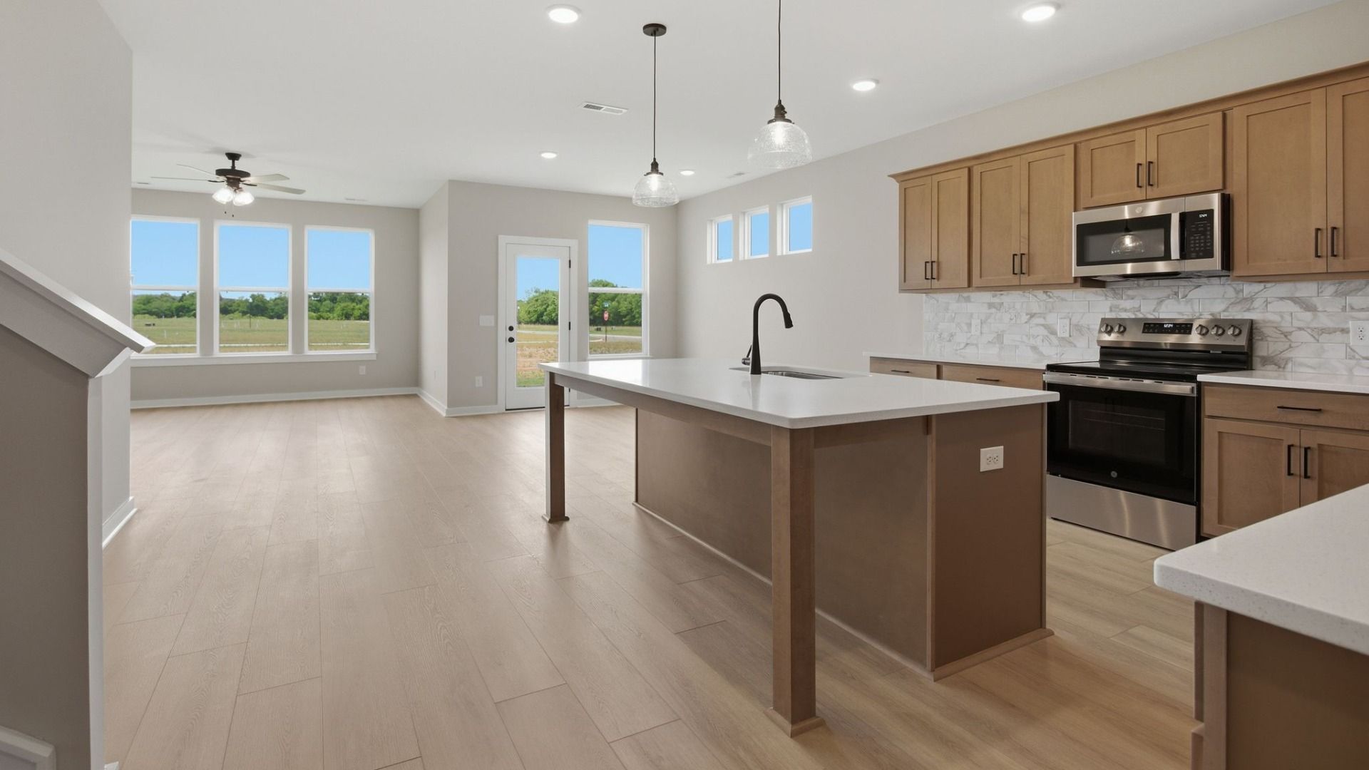 Kitchen with quartz countertops, tile backsplash, and view of gathering room
