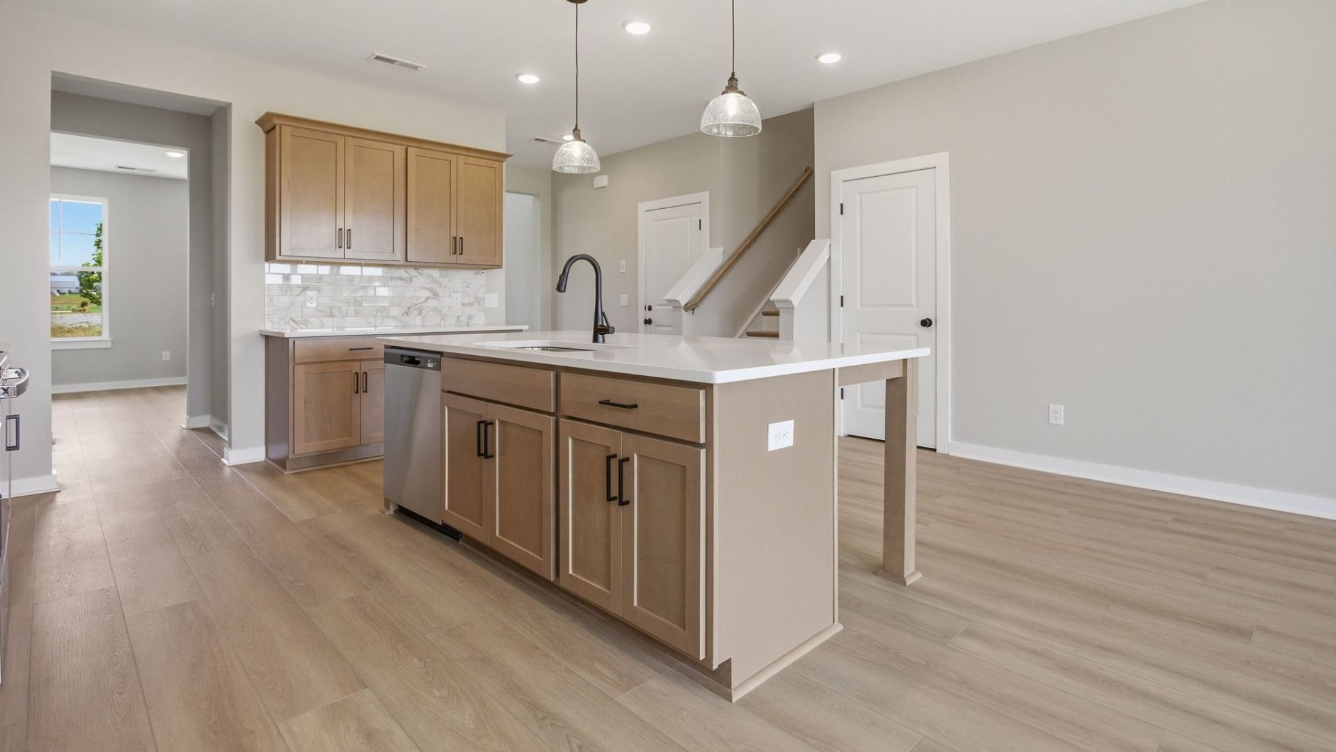 Kitchen with quartz countertops, tile backsplash, and nearby staircase