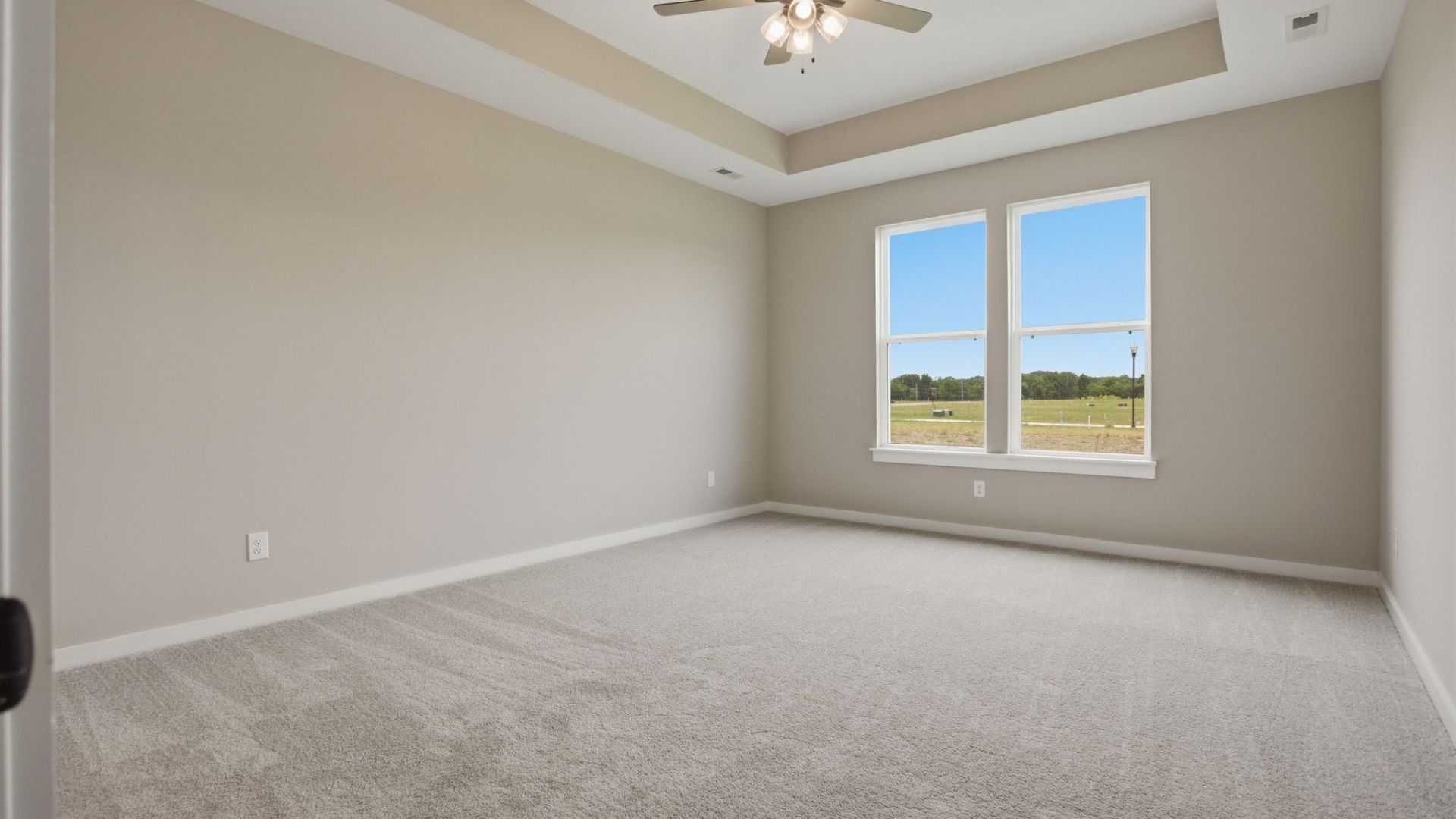 Bedroom with tray ceiling, windows, and ceiling fan