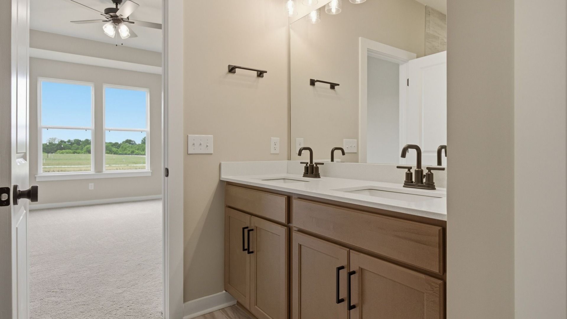 Bathroom with dual vanity leading to primary suite