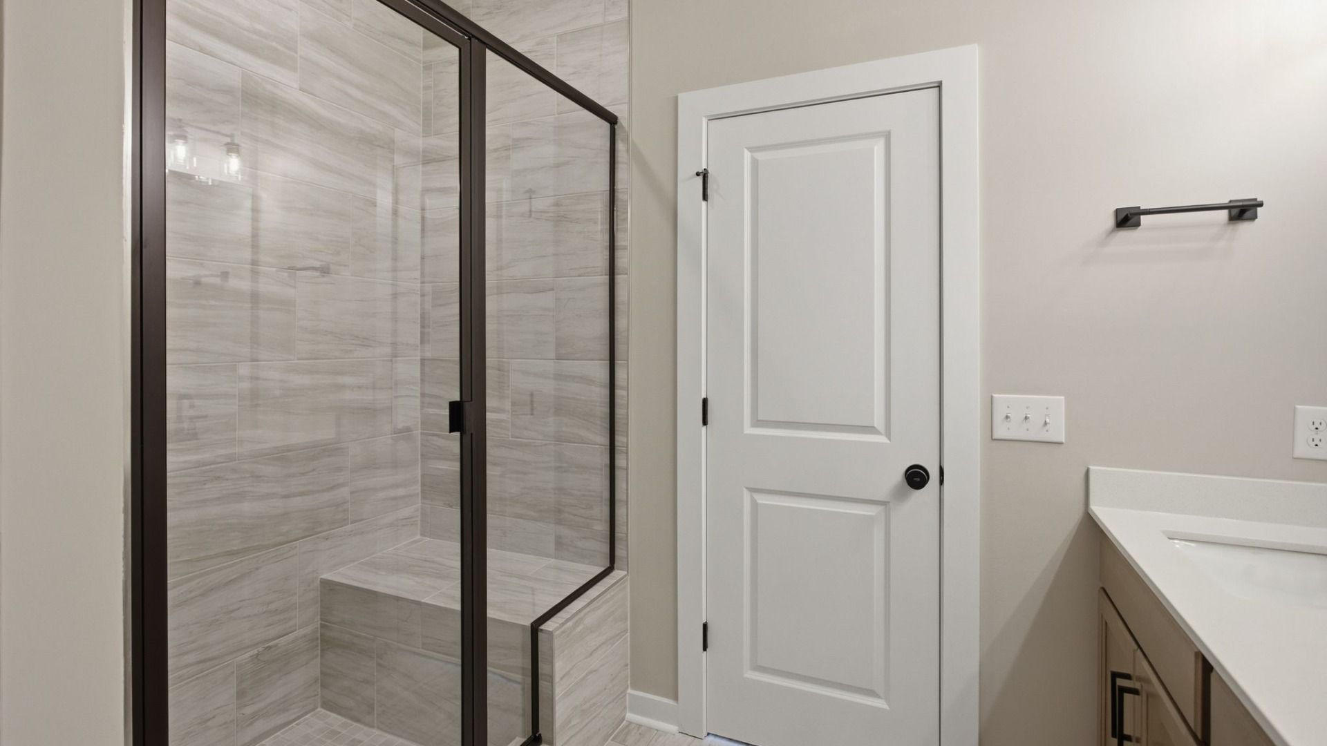 Bathroom with glass enclosed tile shower leading to primary suite