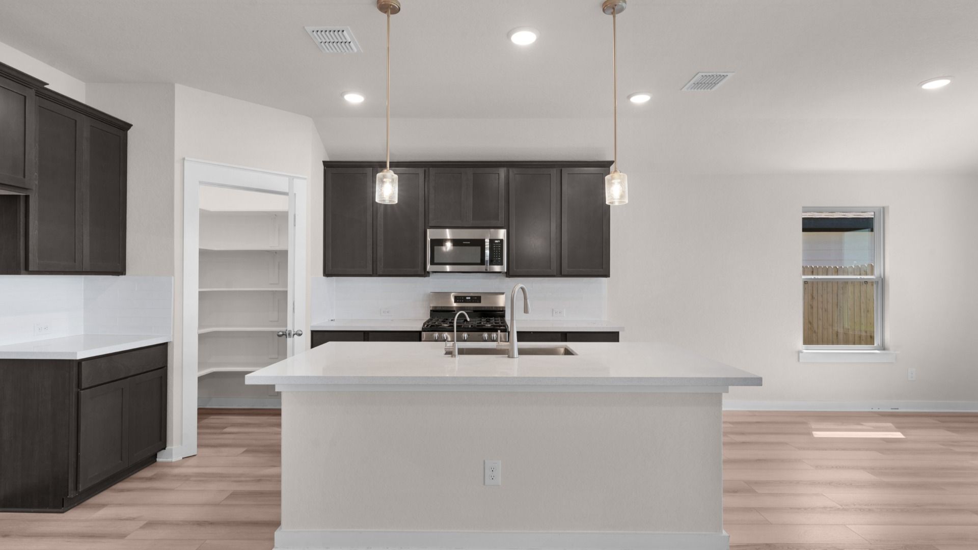 Kitchen with center island, pendant lighting, and rich dark brown cabinets offering a warm, modern feel.