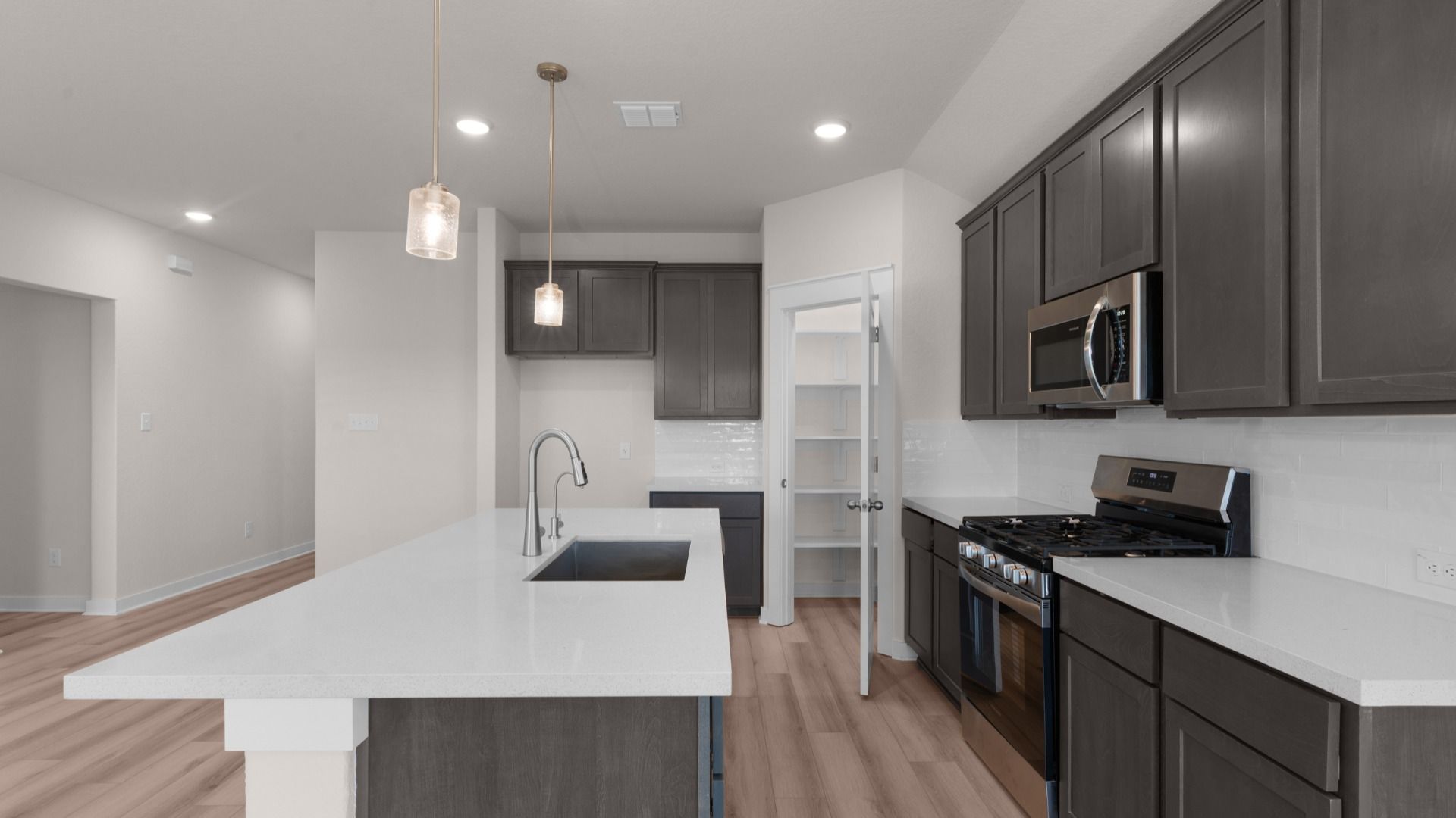 Kitchen with center island, pendant lighting, and rich dark brown cabinets offering a warm, modern feel.