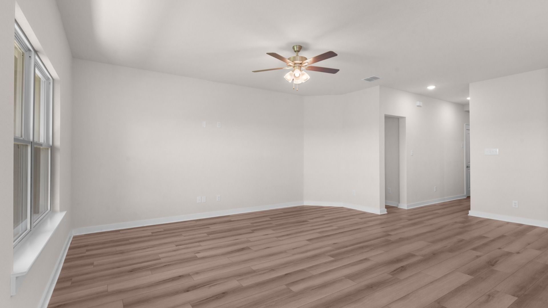 Great room with ceiling fan and large windows, filling the space with natural light and comfortable airflow.