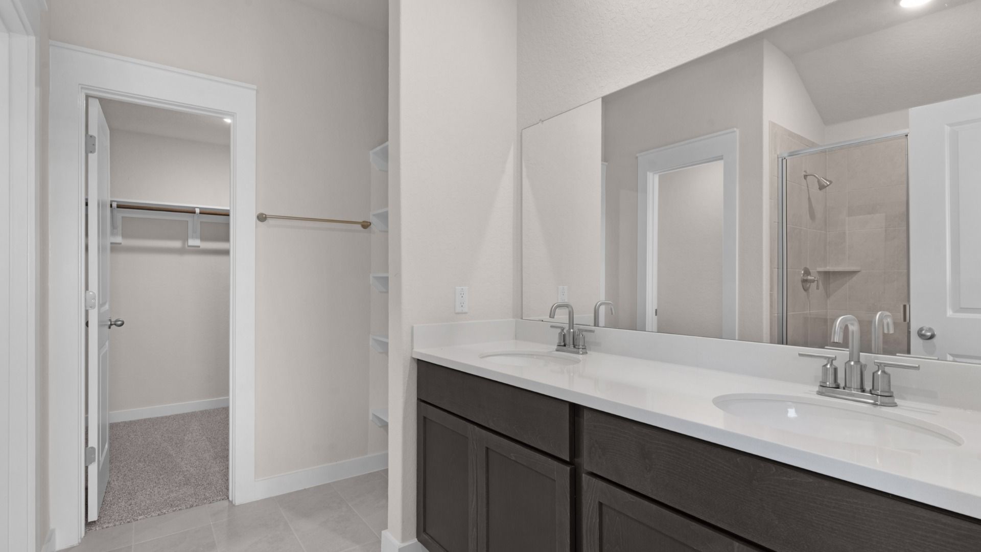 Dual vanity with and a framed glass shower, blending style with practical function.