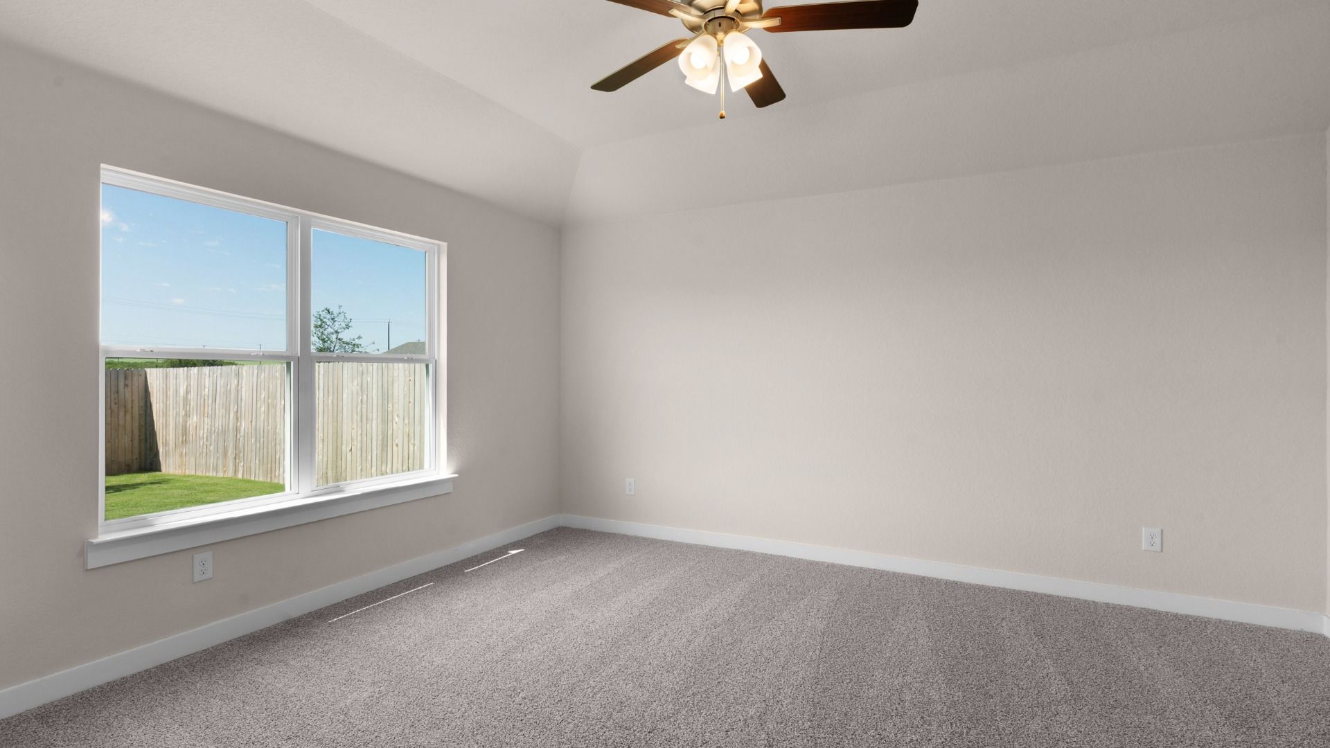 Owner’s suite with ceiling fan and a window overlooking the backyard, creating a relaxing retreat.