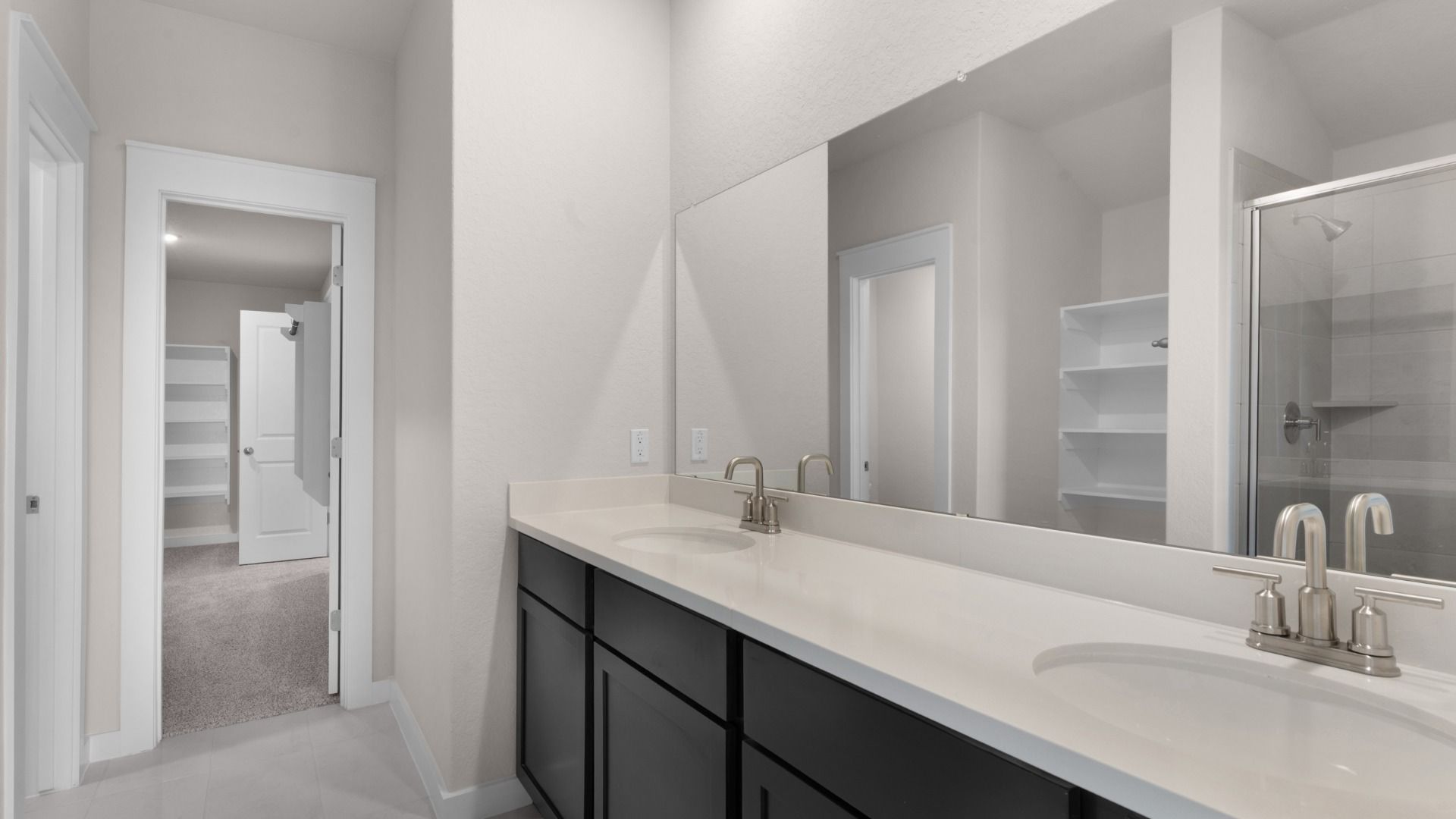Dual vanity with, open shelving for linen storage, and a framed glass shower, blending style with practical function.