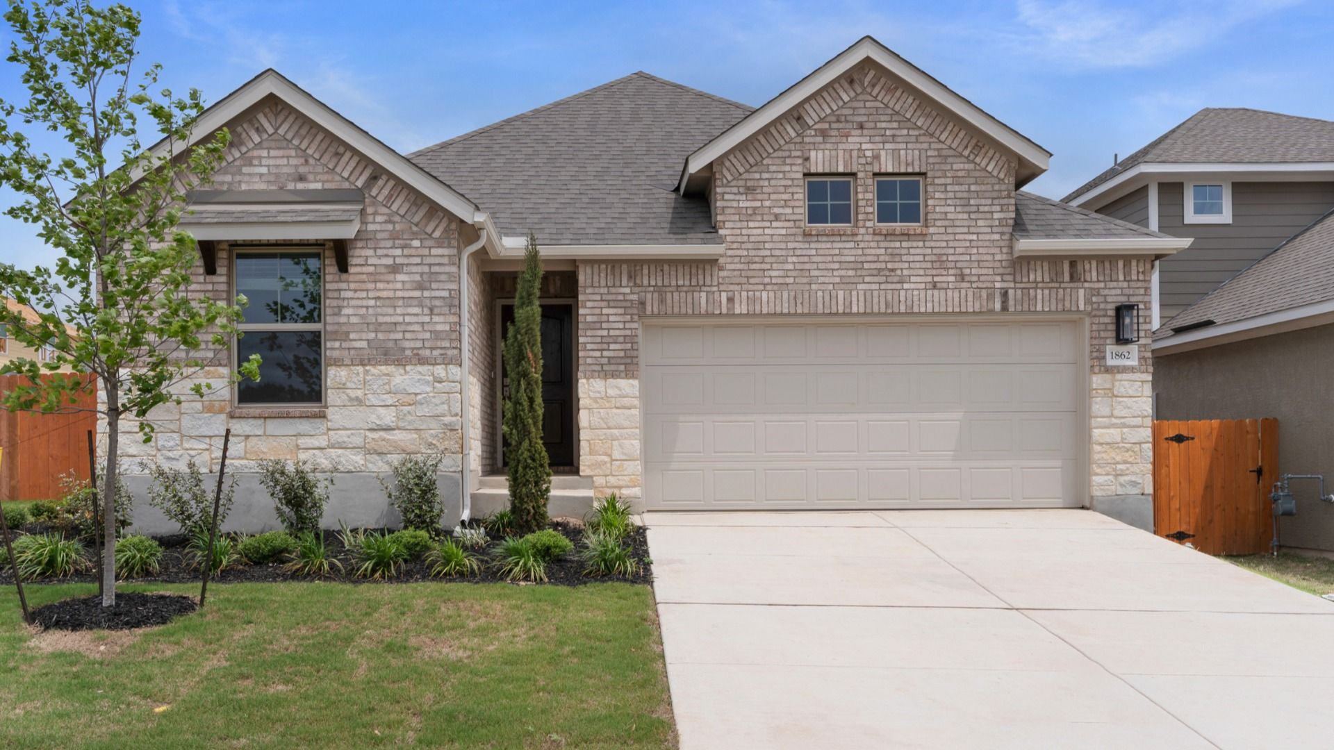 Brick and stone inviting home complete with lush landscaping and architectural detailing.